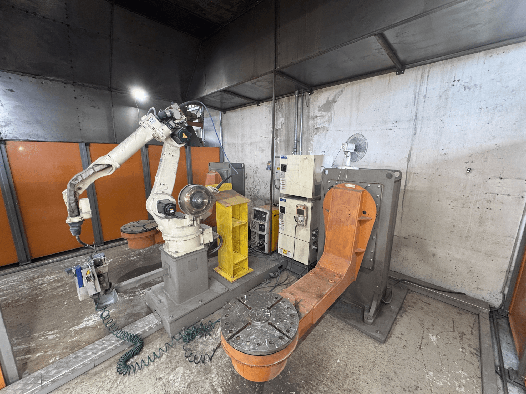DAIHEN VARSTROJ FD-B4L 1GM/2DM roboto ranka pramoninėje aplinkoje, vaizdas iš šono, matomas valdymo skydelis ir pasukamas pagrindas.