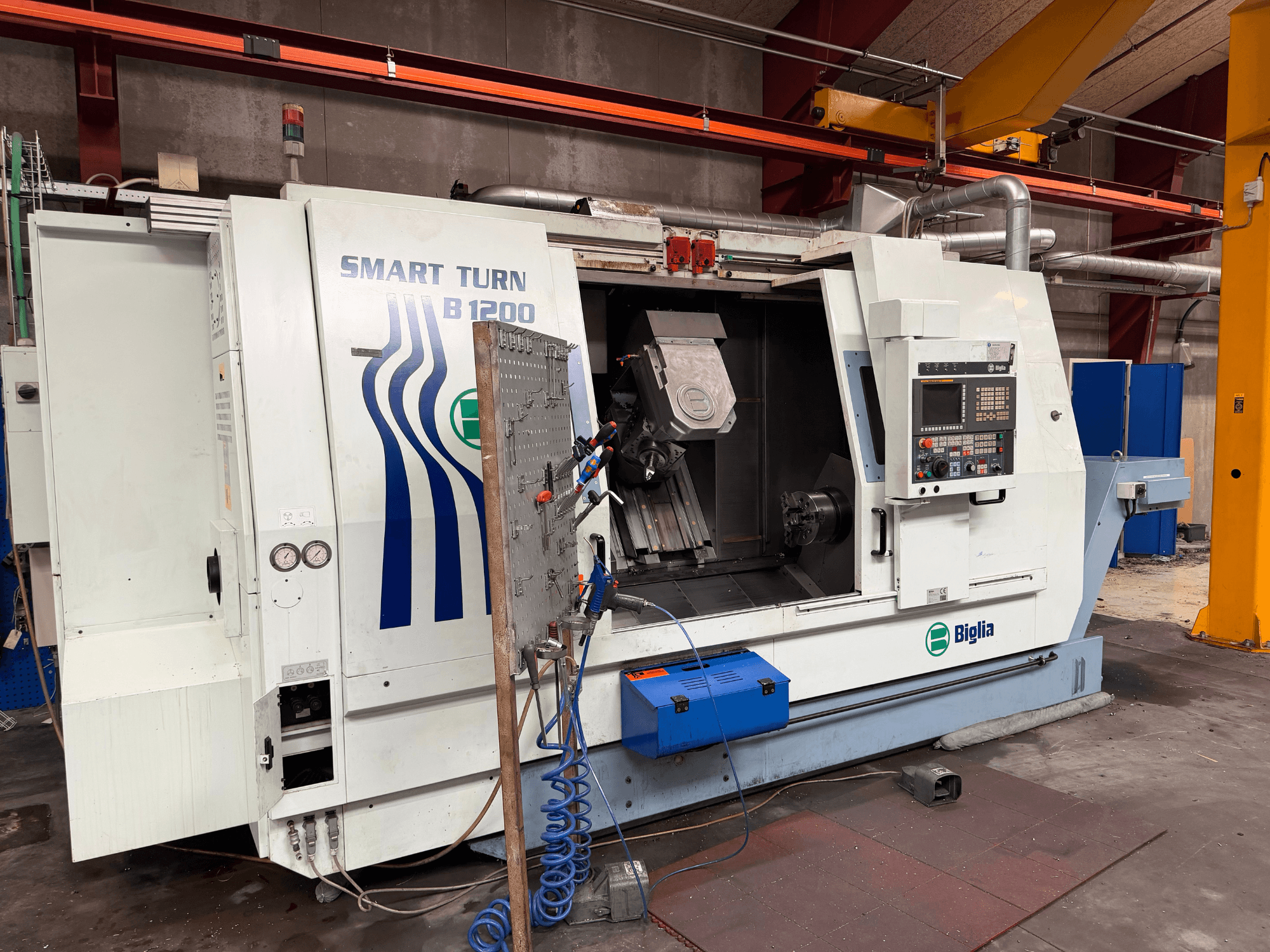 „Biglia B.1200/S-Smart“ tekinimo-frezavimo staklių centras, vaizdas iš priekio; matomi valdymo elementai, suklioje esantis ruošinys ir slėgio matuokliai.