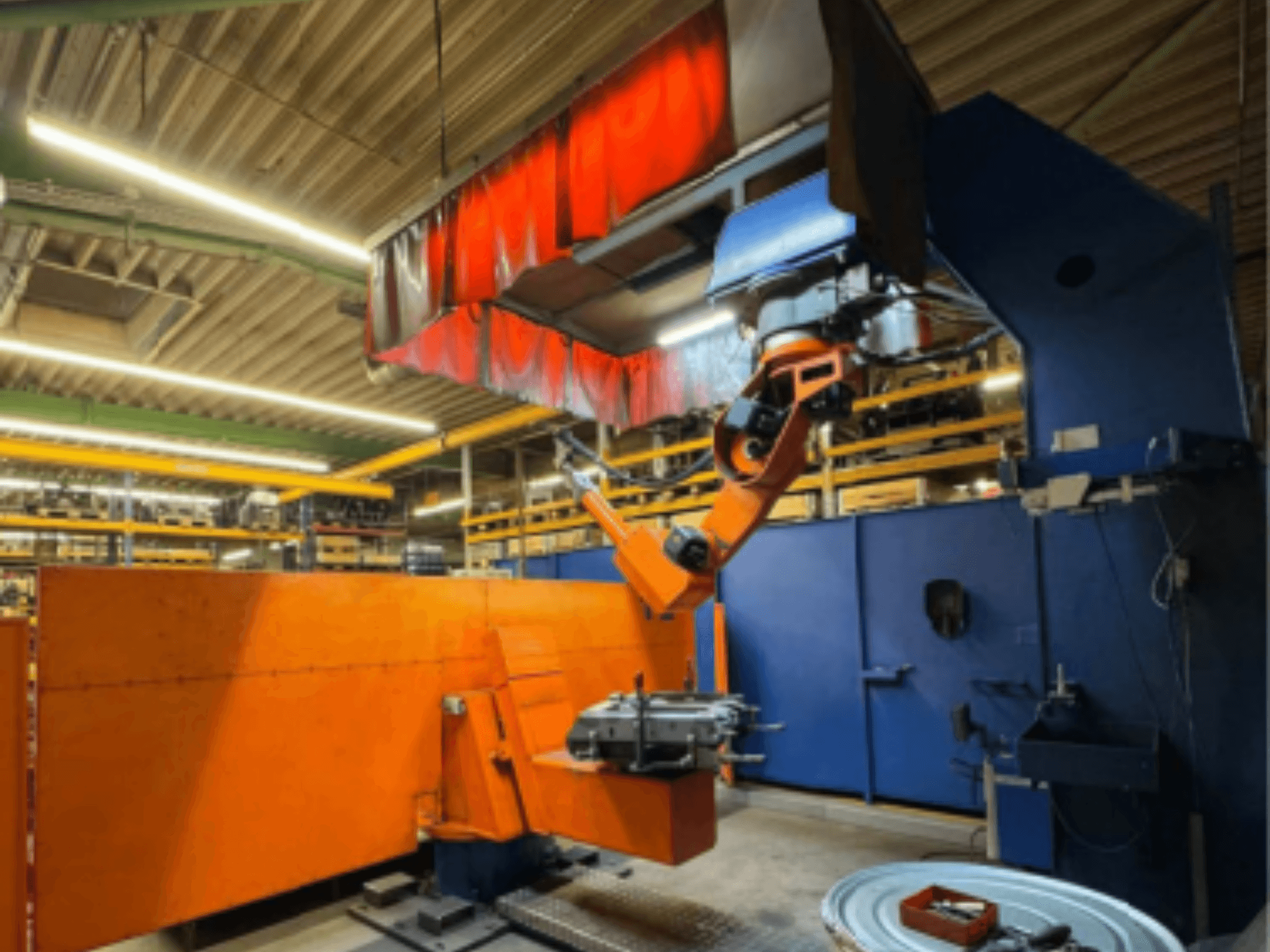 CLOOS Romat 350 e suvirinimo robotas pramoninėje aplinkoje, vaizdas iš priekio su oranžine ranka, laikančia ruošinį po viršutine uždanga.