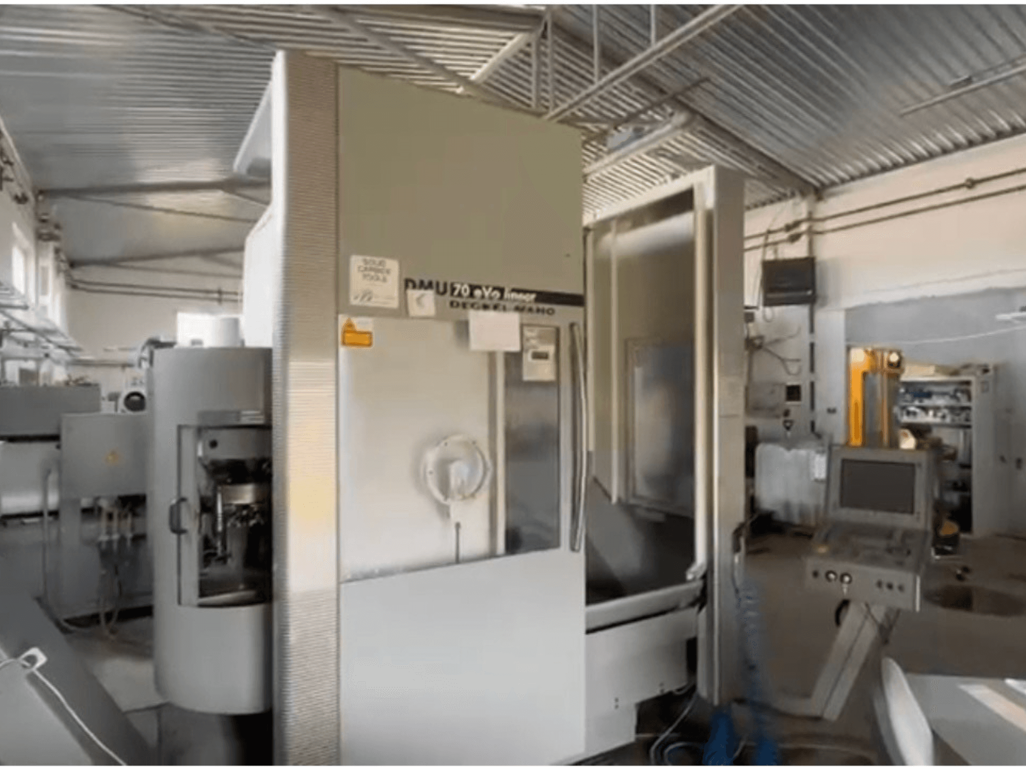 DMU 70 eVo linijinės CNC staklės dirbtuvėse, vaizdas iš priekio, su valdymo skydeliu ir moderniu dizainu.