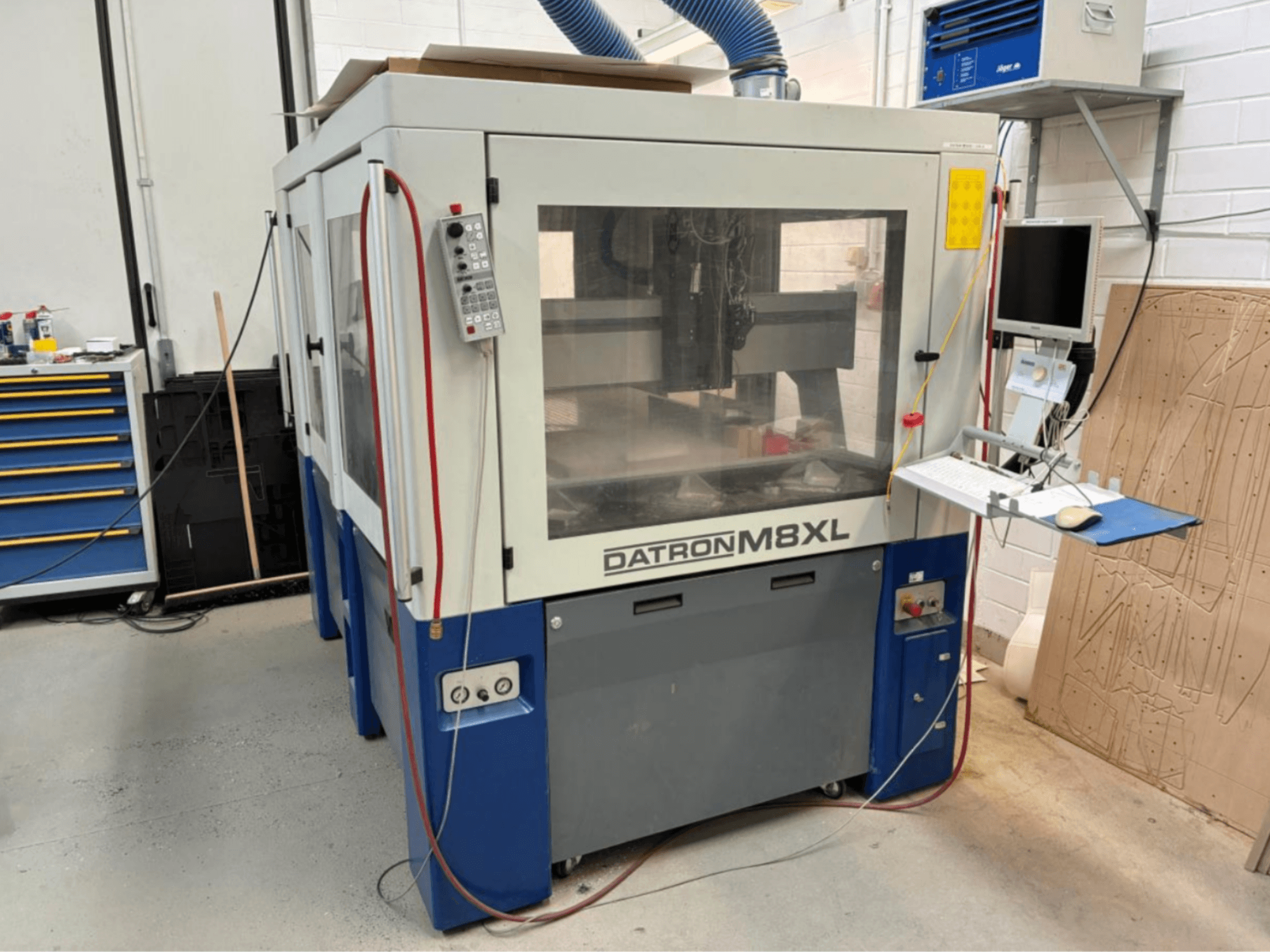 DATRON M8XL CNC staklės dirbtuvėse, vaizdas iš priekio su valdymo skydeliu ir monitoriumi.