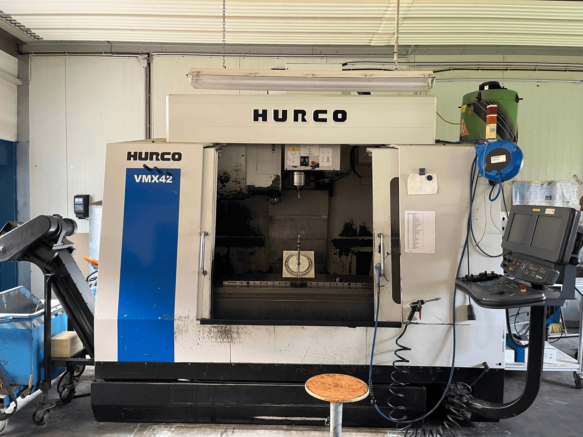 Vertikalaus apdirbimo centro "Hurco VMX 42" šoninis vaizdas, kuriame matomas valdymo skydelis, suklys ir ruošinio nustatymai.