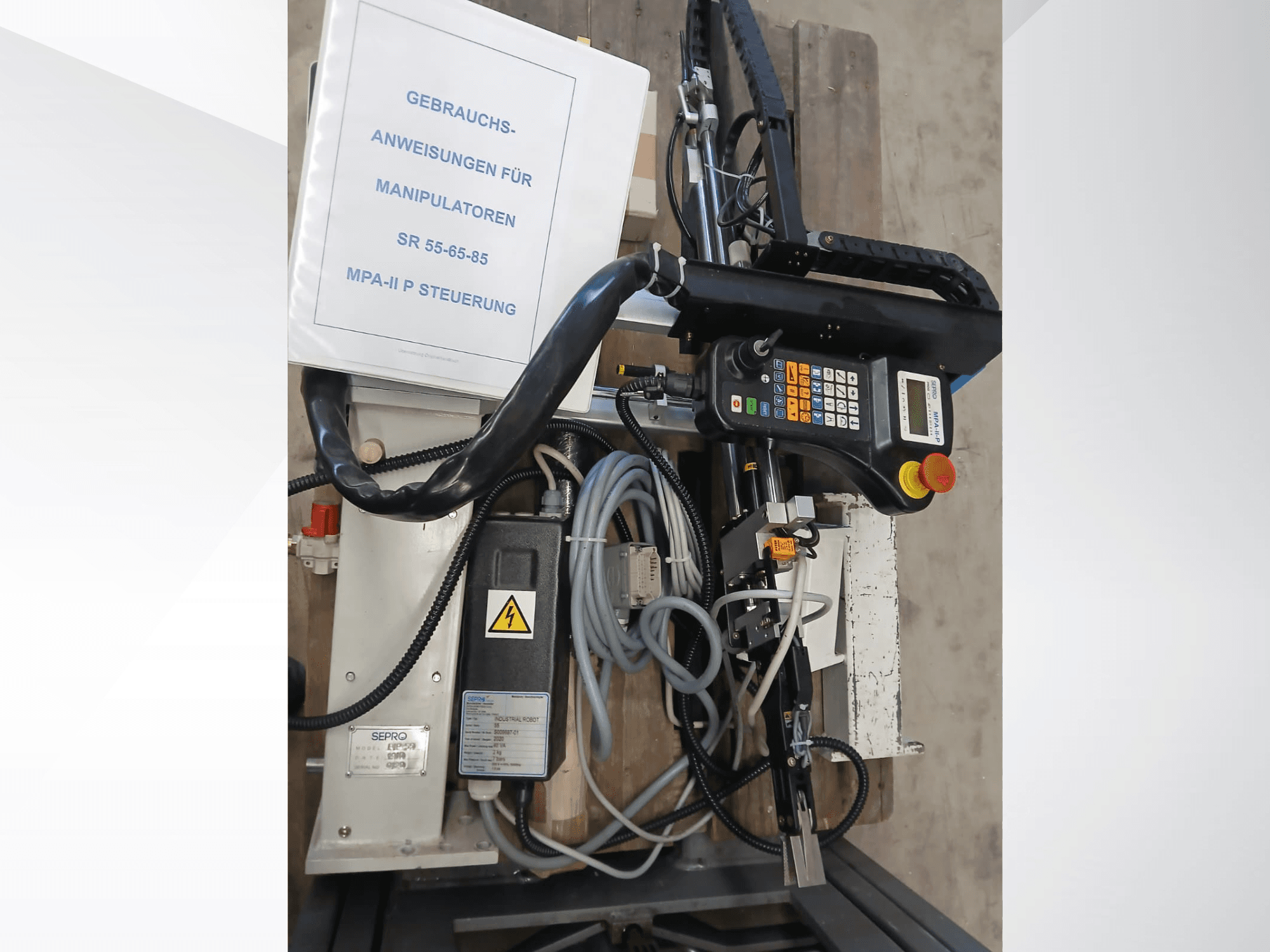 Sepro PIP-55 portalinio roboto valdymo skydelis ir sudedamosios dalys, žiūrint iš šono, matomas naudotojo vadovas.