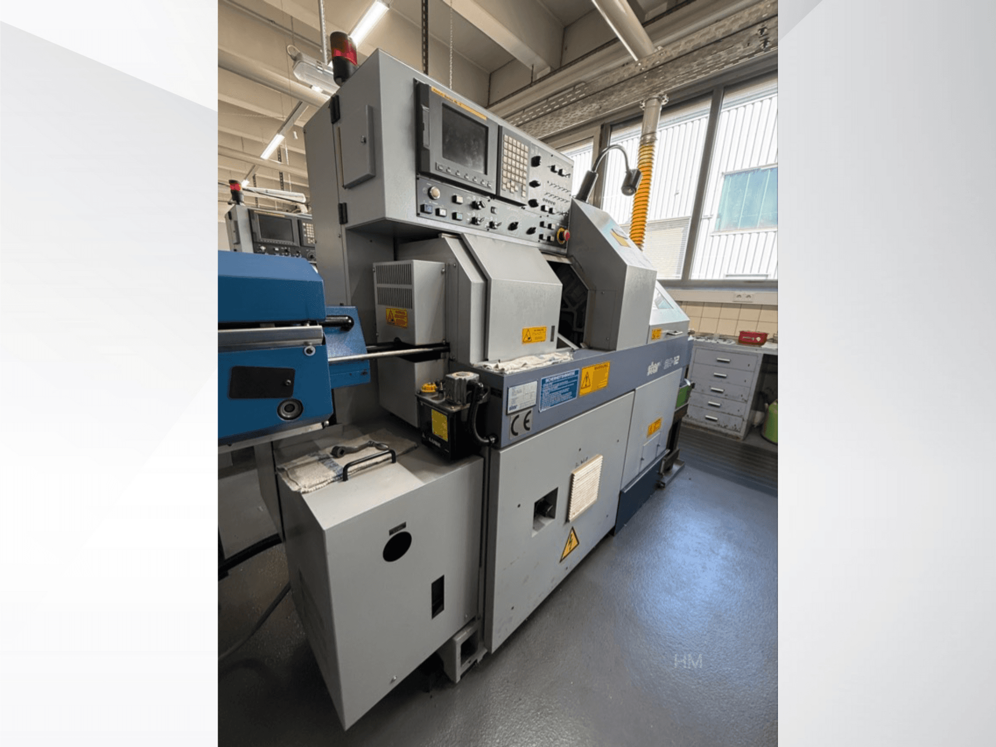 Lithec 3231 mašinos priekinis vaizdas, kuriame matomas valdymo skydelis, variklis ir mėlyna padavimo sekcija gerai apšviestoje pramoninėje aplinkoje.