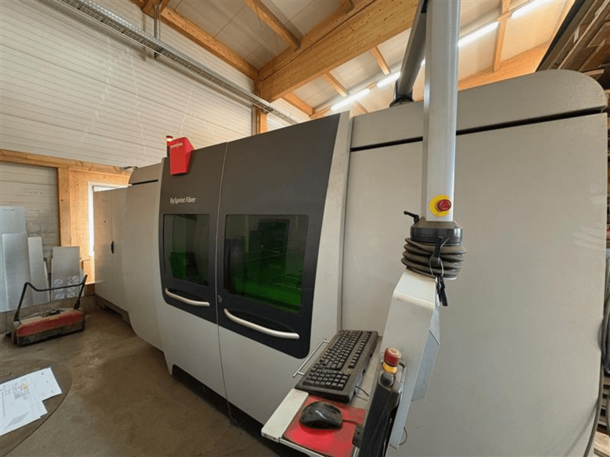 "Bystronic ByJet Fiber" pjaustymo mašina dirbtuvėse, priekinis vaizdas, kuriame matomas valdymo skydelis ir dvigubi žali langai.