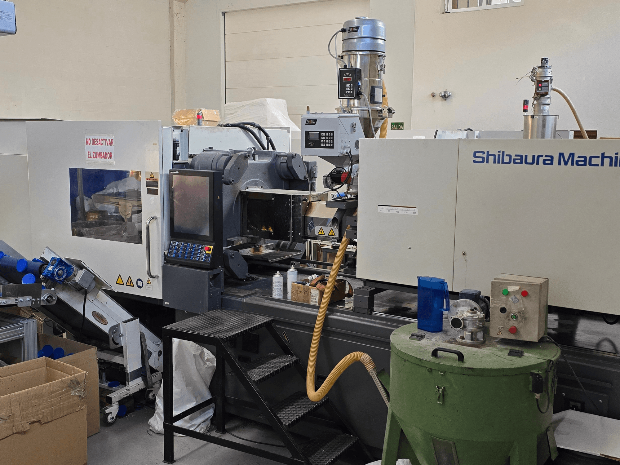 SHIBAURA EC230SXIII-8A elektrinio įpurškimo liejimo mašinos priekinis vaizdas su valdymo skydeliu ir gretima įranga.