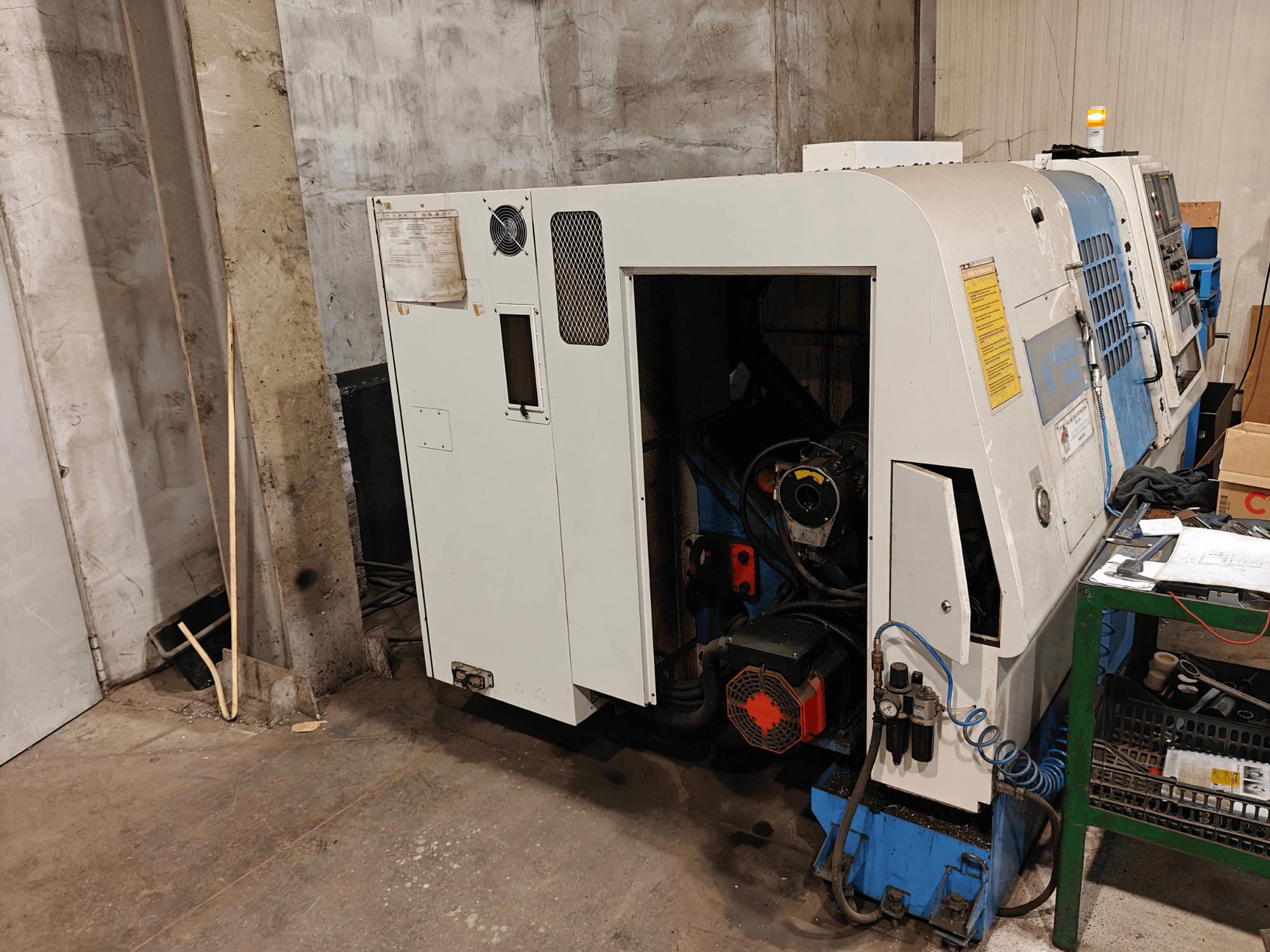 Tekinimo staklių (markė ir modelis nenurodyti) priekinis vaizdas, kuriame matomi valdymo įtaisai ir variklio komponentai.