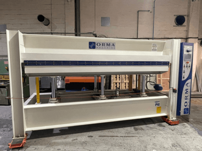 Hidraulinis presas "ORMA machinery", vaizdas iš priekio, sidabrinė apdaila, valdymo skydelis dešinėje ir vertikalūs presavimo stūmokliai.