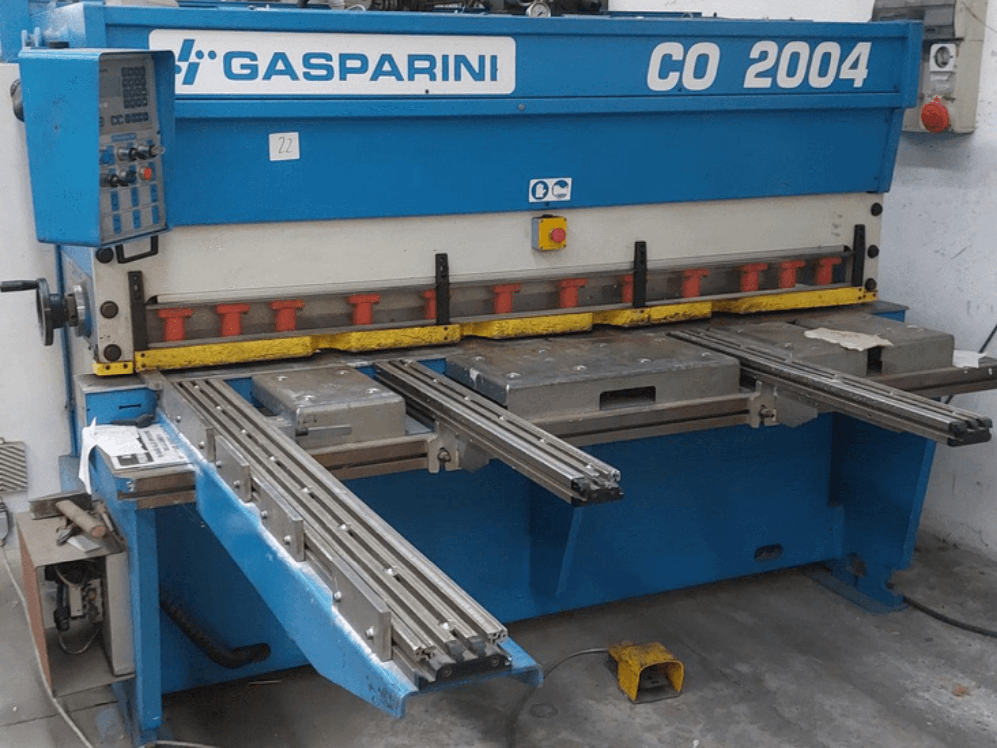 Hidraulinė kirpimo staklė „GASPARINI CO/2004“, vaizdas iš priekio, su valdymo pultu ir metalo pjovimo stalais su slankiosiomis bėgėmis.