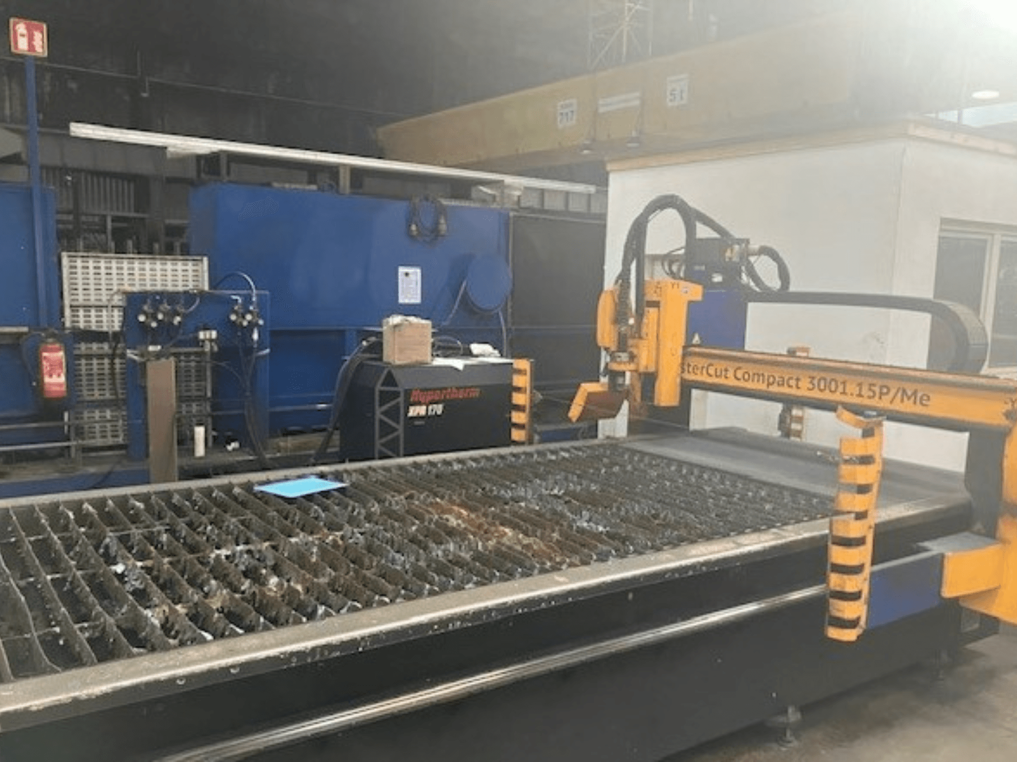 Hypertherm MasterCut Compact 3001.15P/Me plazminio pjovimo staklės šoniniu vaizdu, pjovimo stalas ir valdymo skydelis.