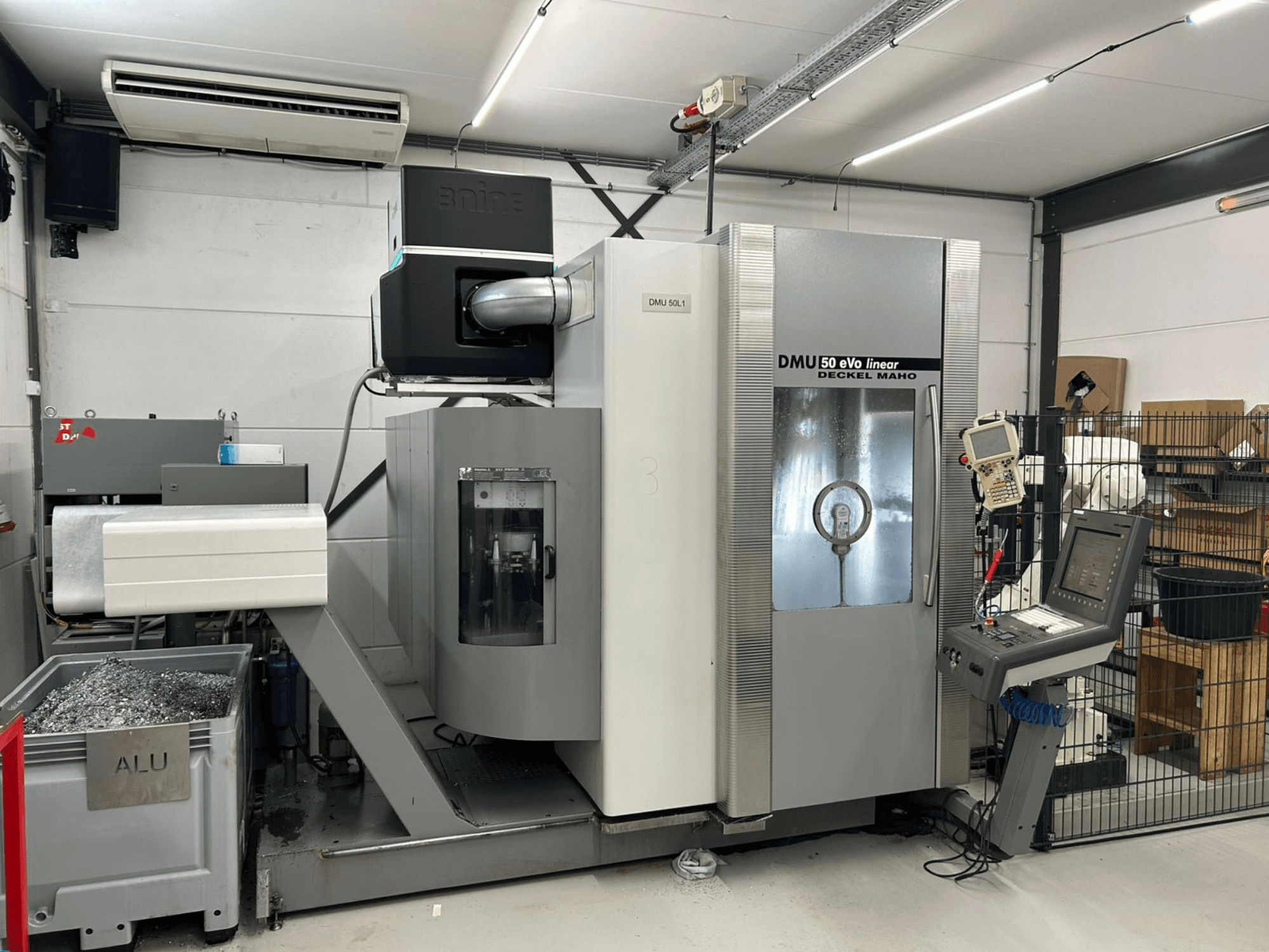 Deckel Maho linijinės frezavimo staklės DMU 50 eVo, vaizdas iš priekio, su valdymo skydeliu ir drožlių konteineriu.