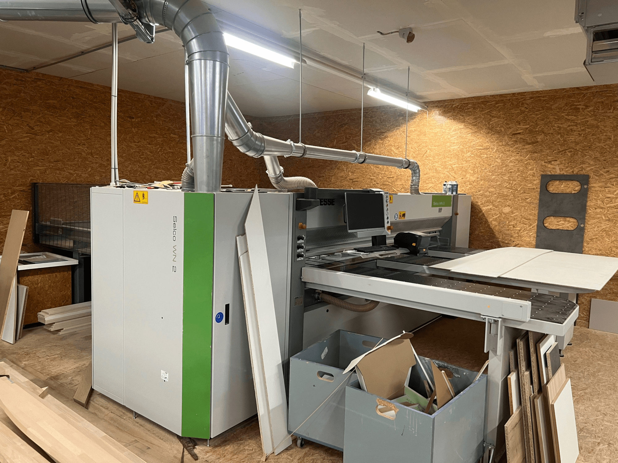 BIESSE Selco WN 2 plokščių pjūklas dirbtuvėse, su dideliu pjovimo stalu ir dulkių nusiurbimo sistema, vaizdas iš šono.