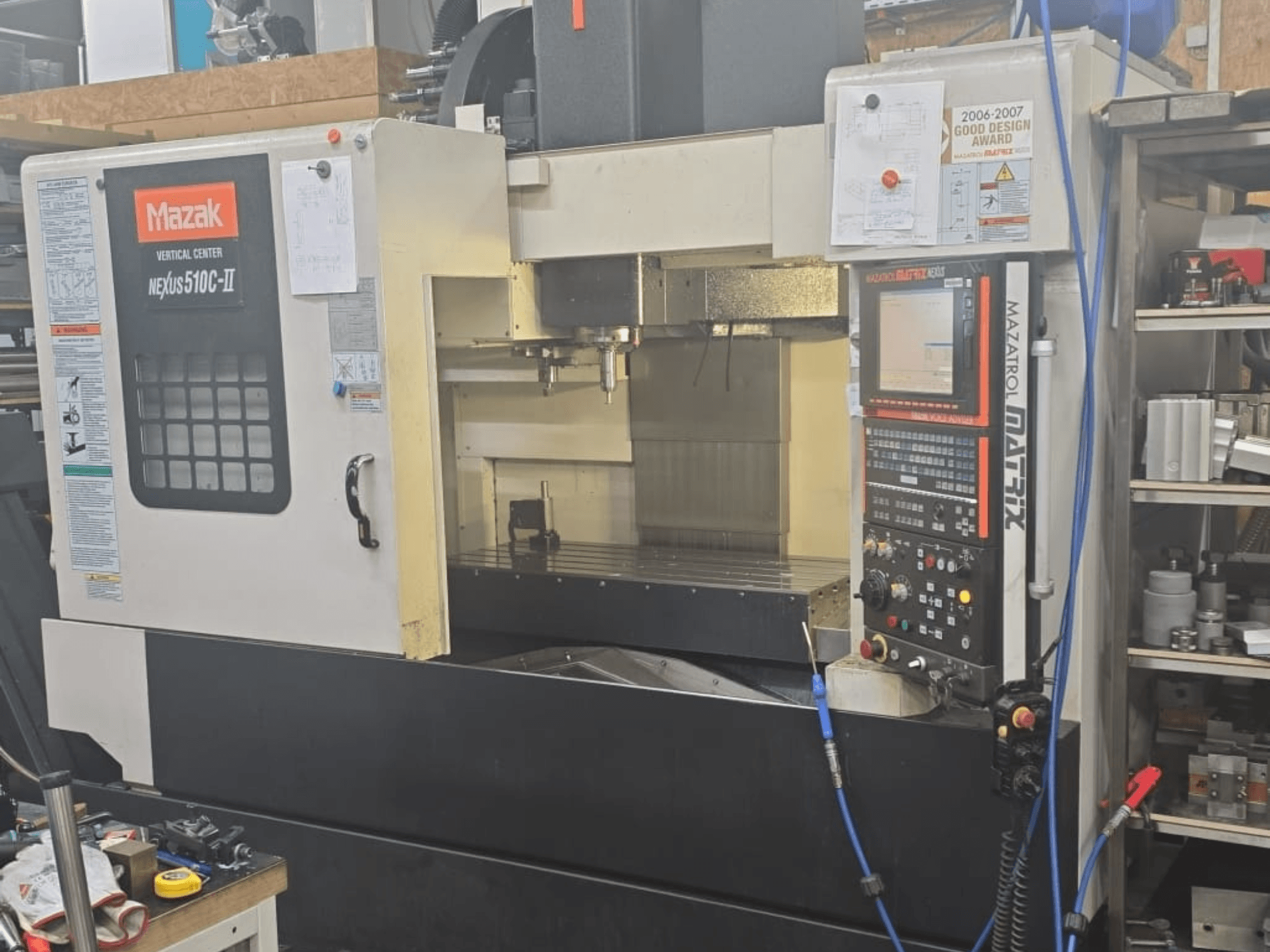 Mazak VERTIKALINIS CENTRAS NEXUS 510C-II, priekinis vaizdas, kuriame matomas valdymo skydelis, apdirbimo zona ir darbinės funkcijos.