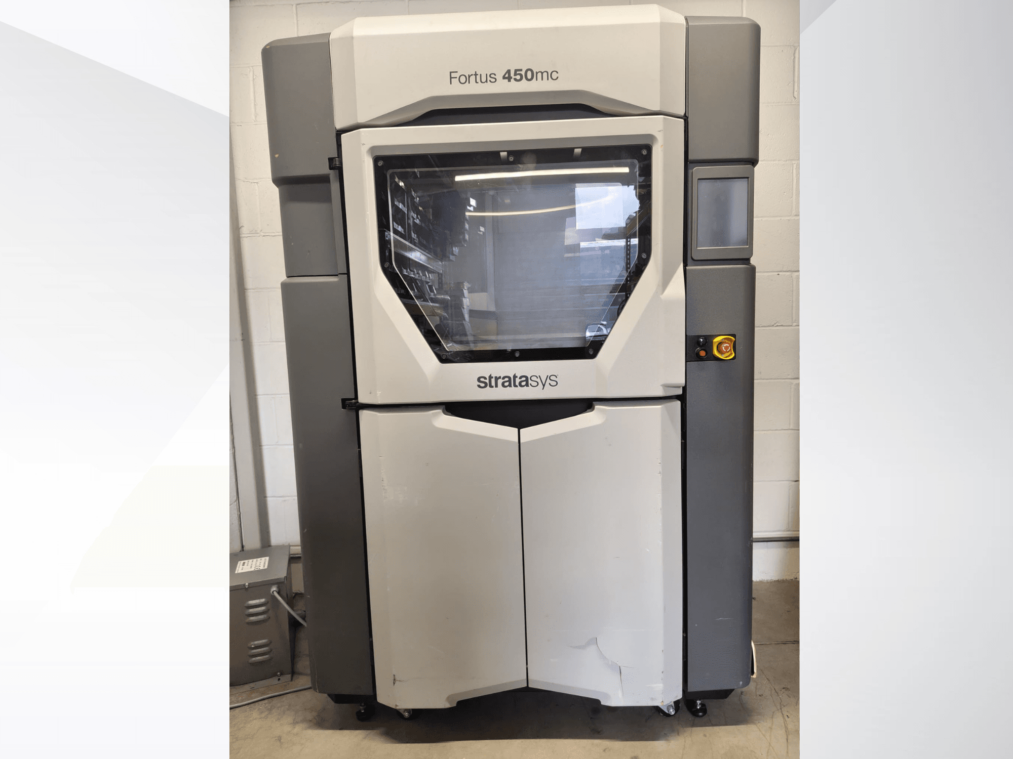 „Stratasys Fortus 450mc“ plastiko apdirbimo staklės, vaizdas iš priekio, su dideliu langeliu, valdymo skydeliu ir pramoniniu dizainu.