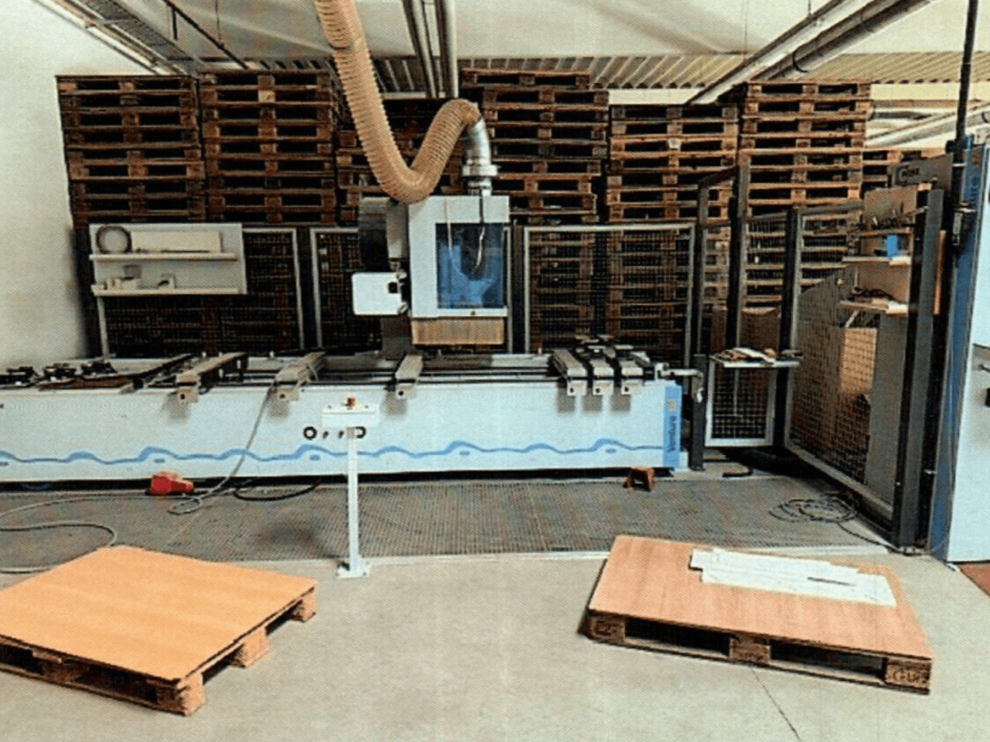 CNC medienos apdirbimo centras Weeke Venture 1M dirbtuvėse, vaizdas iš priekio su matomais mediniais padėklais ir pramonine įranga.