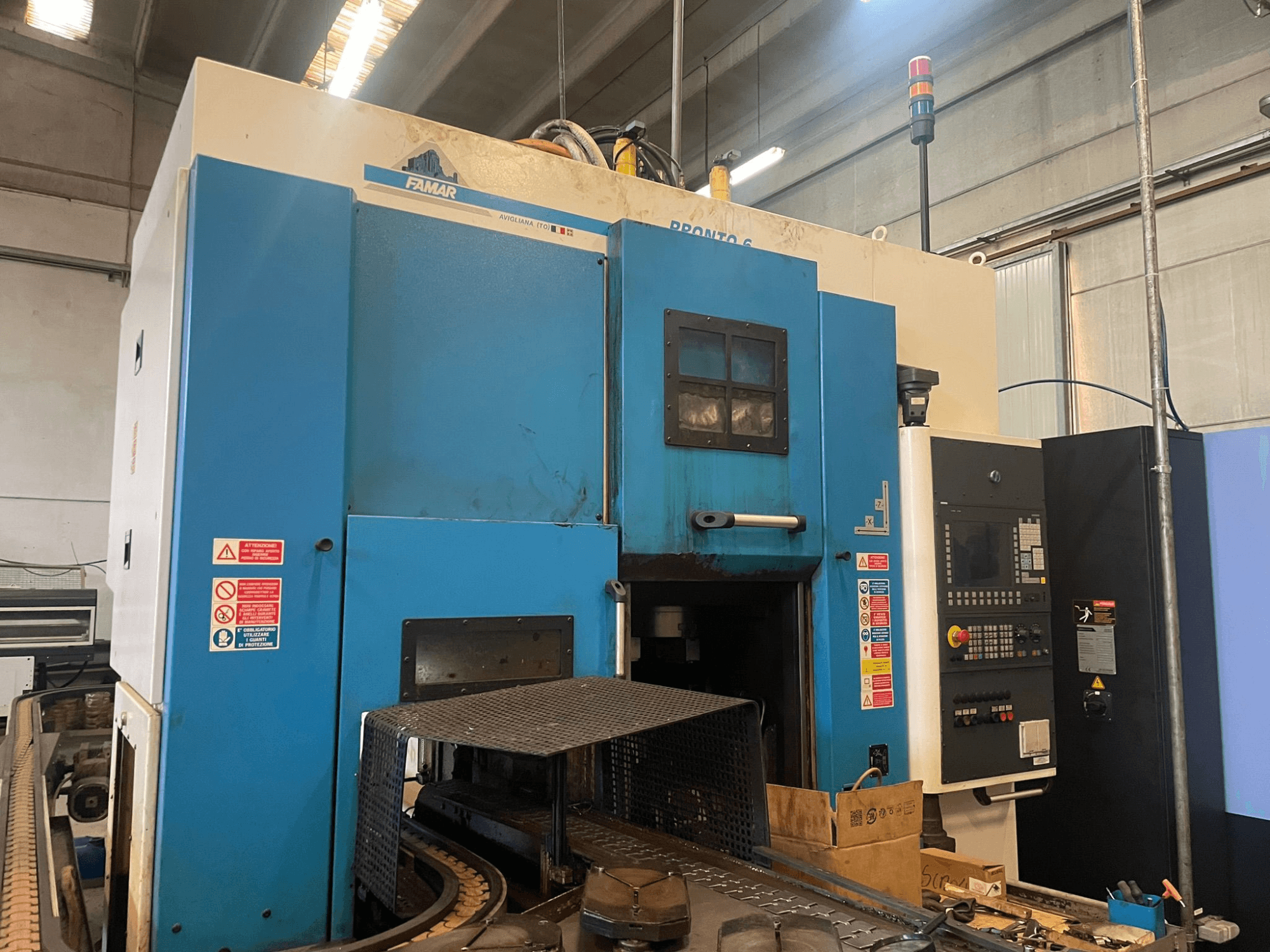 Vertikalios tekinimo staklės "Famar Pronto 6" dirbtuvėse, šoninis vaizdas, kuriame matomas valdymo skydelis, veikimo funkcijos ir saugos etiketės.