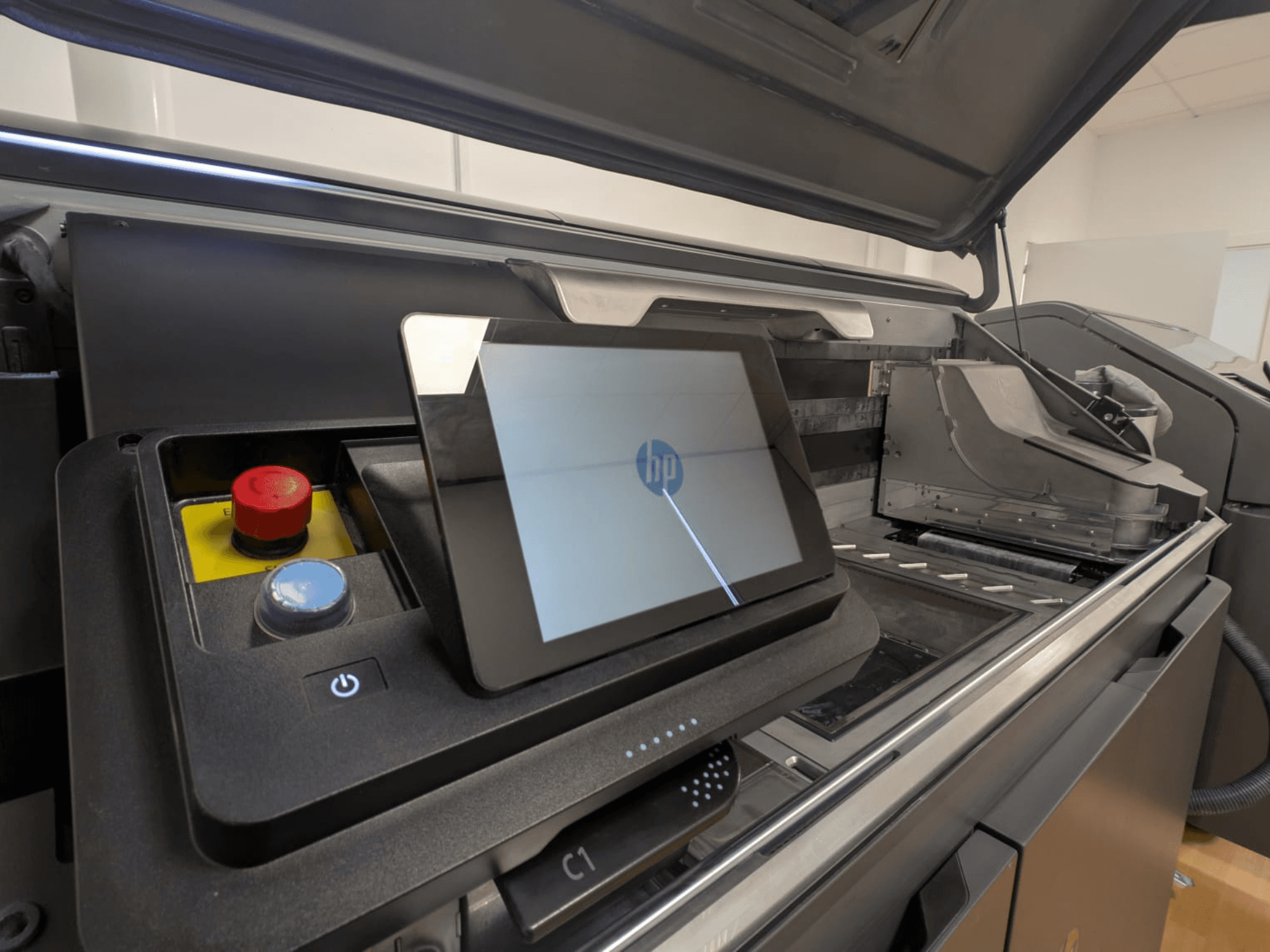 HP spausdintuvo valdymo skydelis, kuriame matyti planšetinis ekranas, raudoni ir mėlyni mygtukai ir šoninis spausdintuvo vidaus komponentų vaizdas.