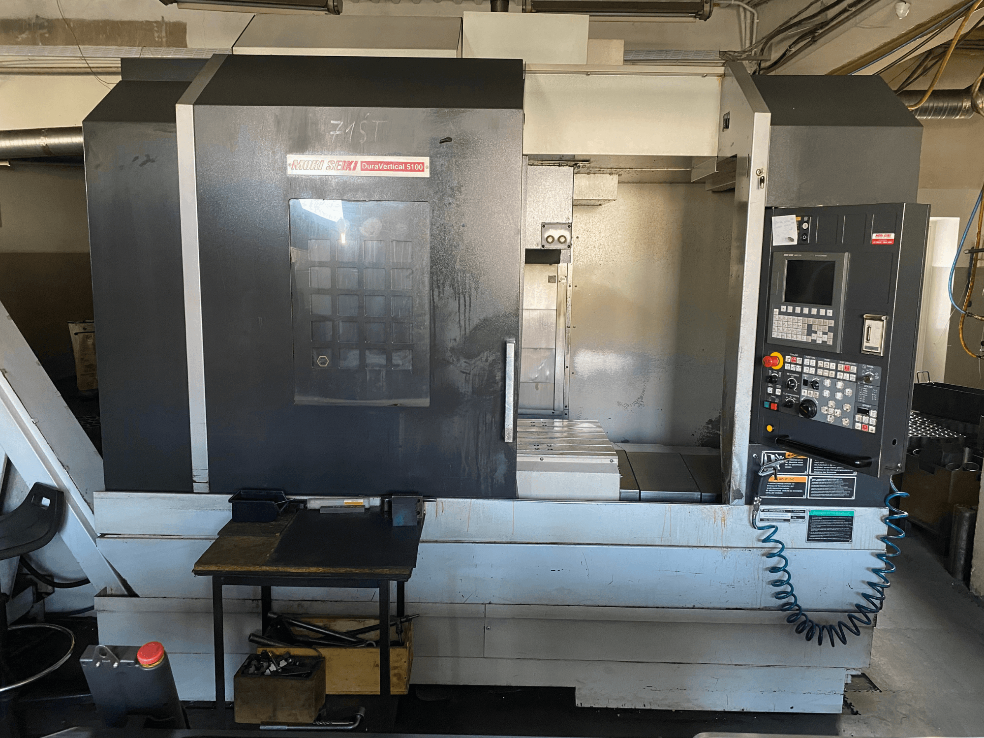 „MORI SEIKI DuraVertical 5100“ vaizdas iš priekio, kuriame matomas valdymo pultas, darbo zona ir staklių detalės.