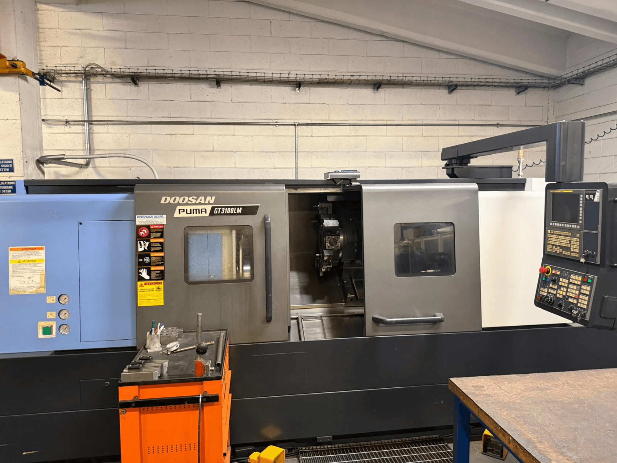 Horizontaliųjų tekinimo staklių DOOSAN PUMA GT3100LM priekinis vaizdas, kuriame matyti valdymo skydelis ir darbo zona su įrankiais.