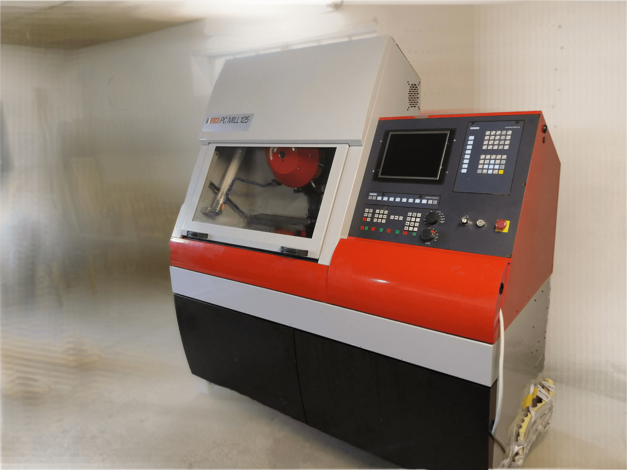 EMCO PC MILL 125 vertikalusis apdirbimo centras, vaizdas iš priekio su valdymo skydeliu ir matoma apdirbimo zona.