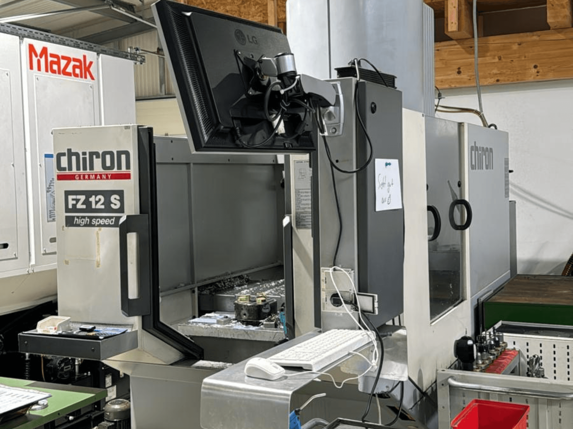 Vertikalus CHIRON FZ 12 S greitaeigio apdirbimo centro vaizdas su valdymo ekranu ir apdirbimo proceso nuolaužomis.