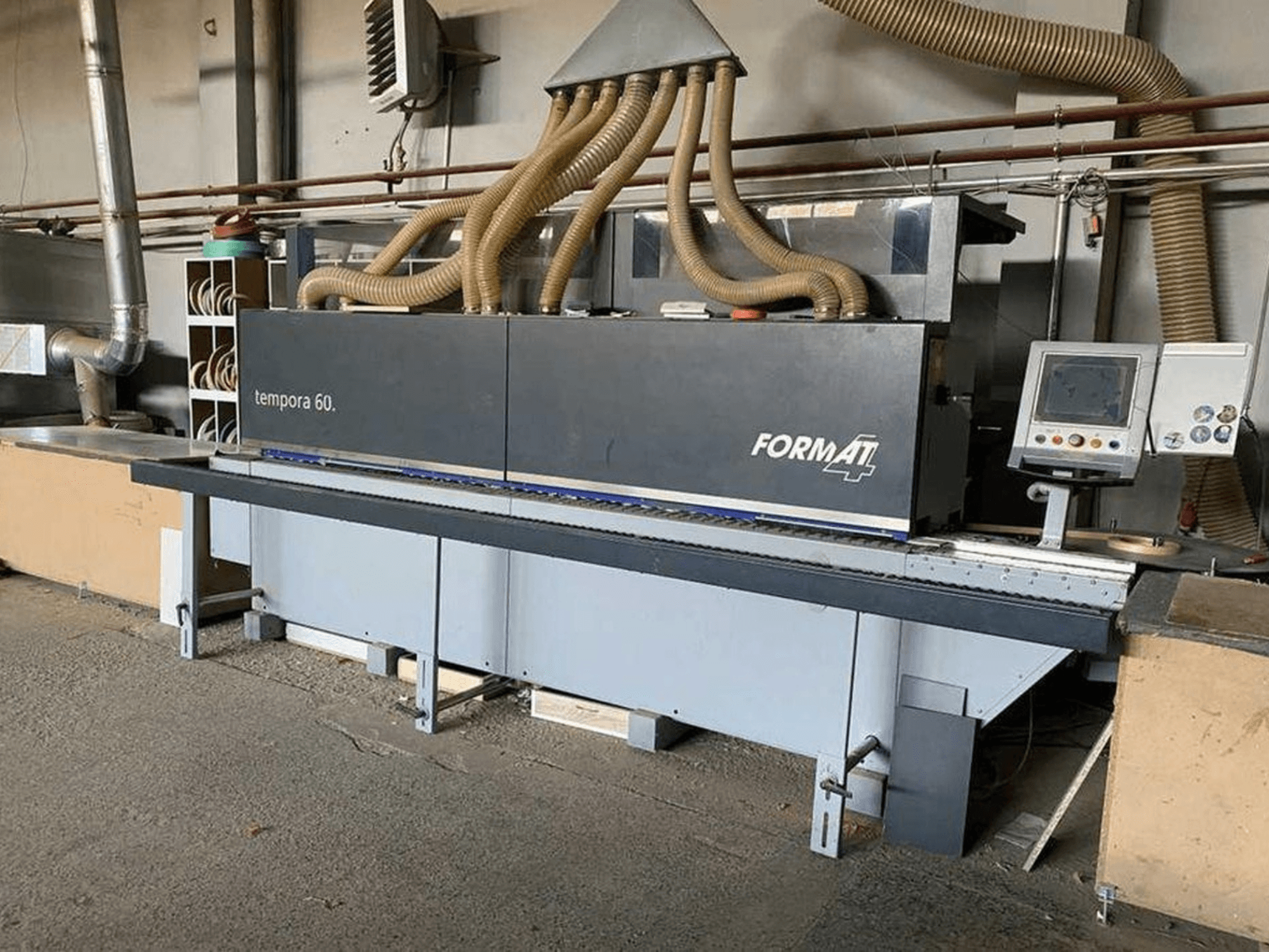 FORMAT4 Tempora 60 briaunų apipjaustymo staklės iš šono, su keliomis žarnomis ir valdymo skydeliu su mygtukais bei ekranu.