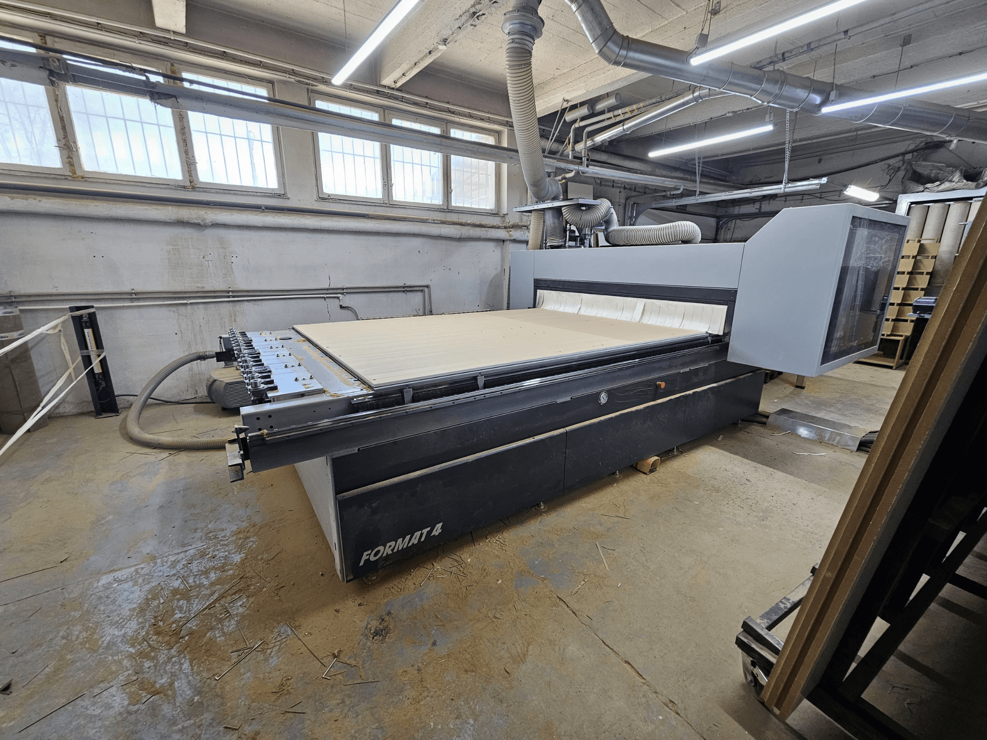 CNC maršrutizatorius FORMAT4 Profit H80 21.31, šoninis vaizdas, rodantis didelį darbo stalą ir valdymo skydelį dirbtuvėse.