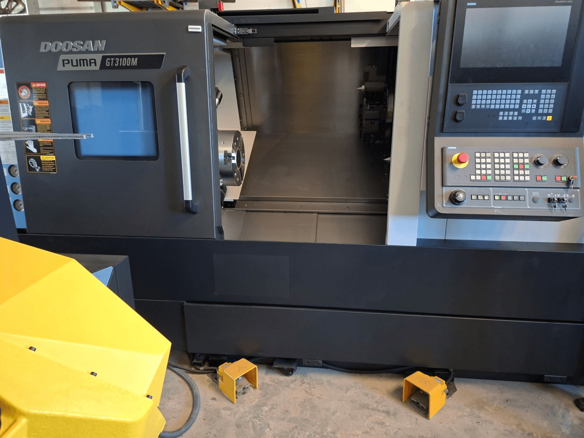 DOOSAN Puma GT 3100 M horizontaliojo tekinimo staklės iš priekio, matomas valdymo skydelis, atviras bokštelis ir vidinė darbo erdvė.