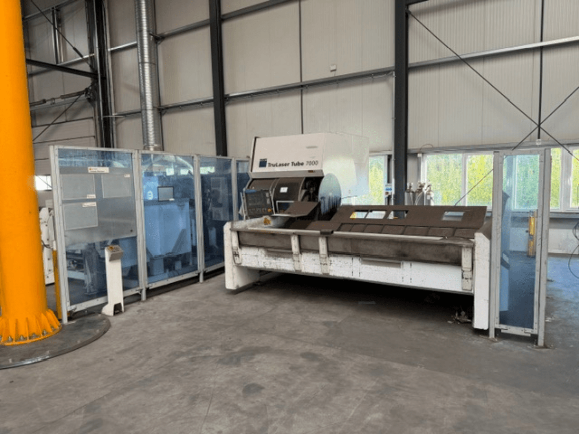 „TruLaser Tube 7000“ (gamintojas – TRUMPF) – vamzdžių pjovimo staklių vaizdas iš priekio gerai apšviestoje pramoninėje aplinkoje, matomi valdymo elementai.