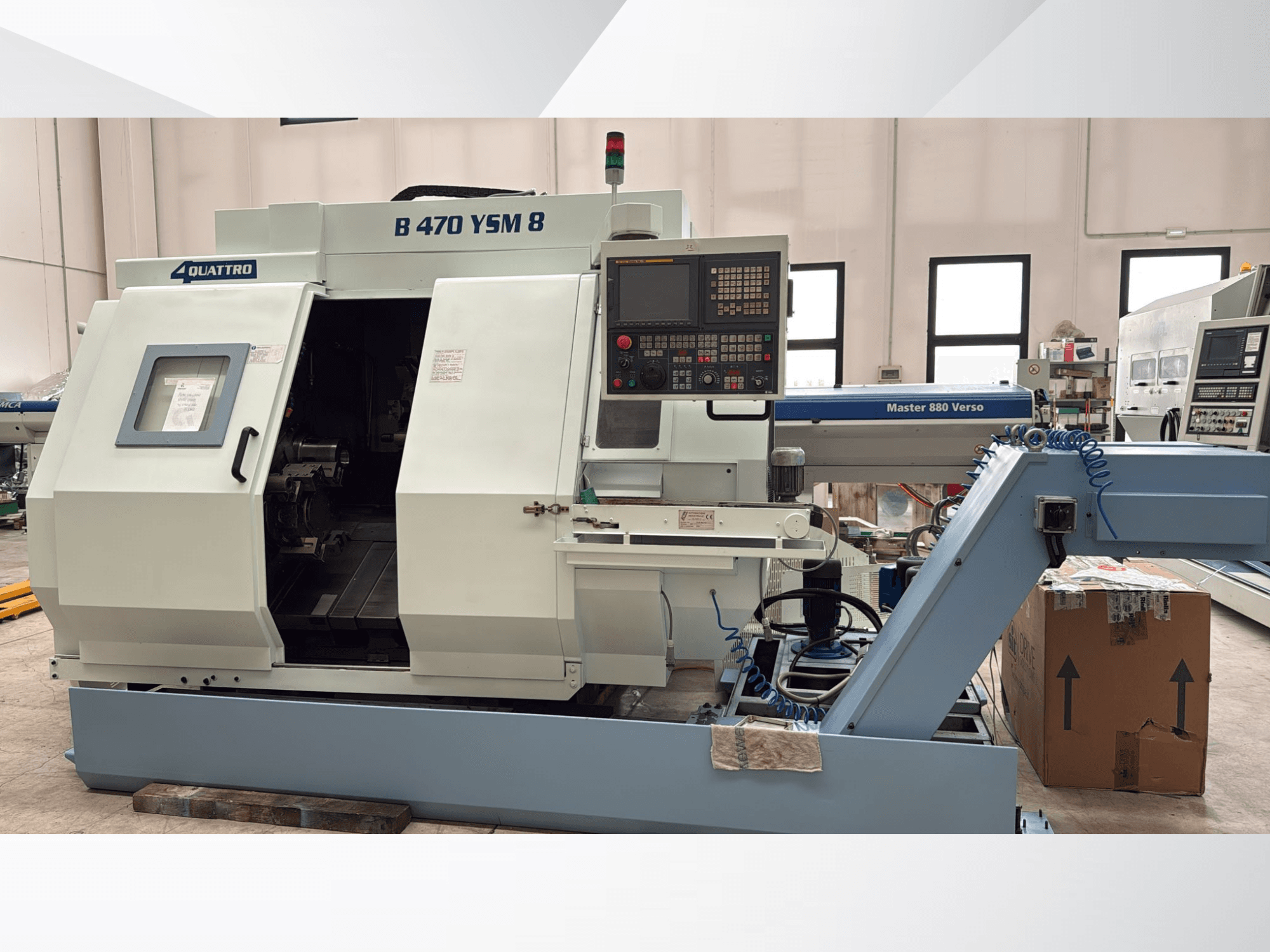 "Biglia B470 YSM" tekinimo frezavimo centras, priekinis vaizdas, kuriame matomas valdymo skydelis, atidarytas liukas ir darbo vieta su viduje esančiais įrankiais.