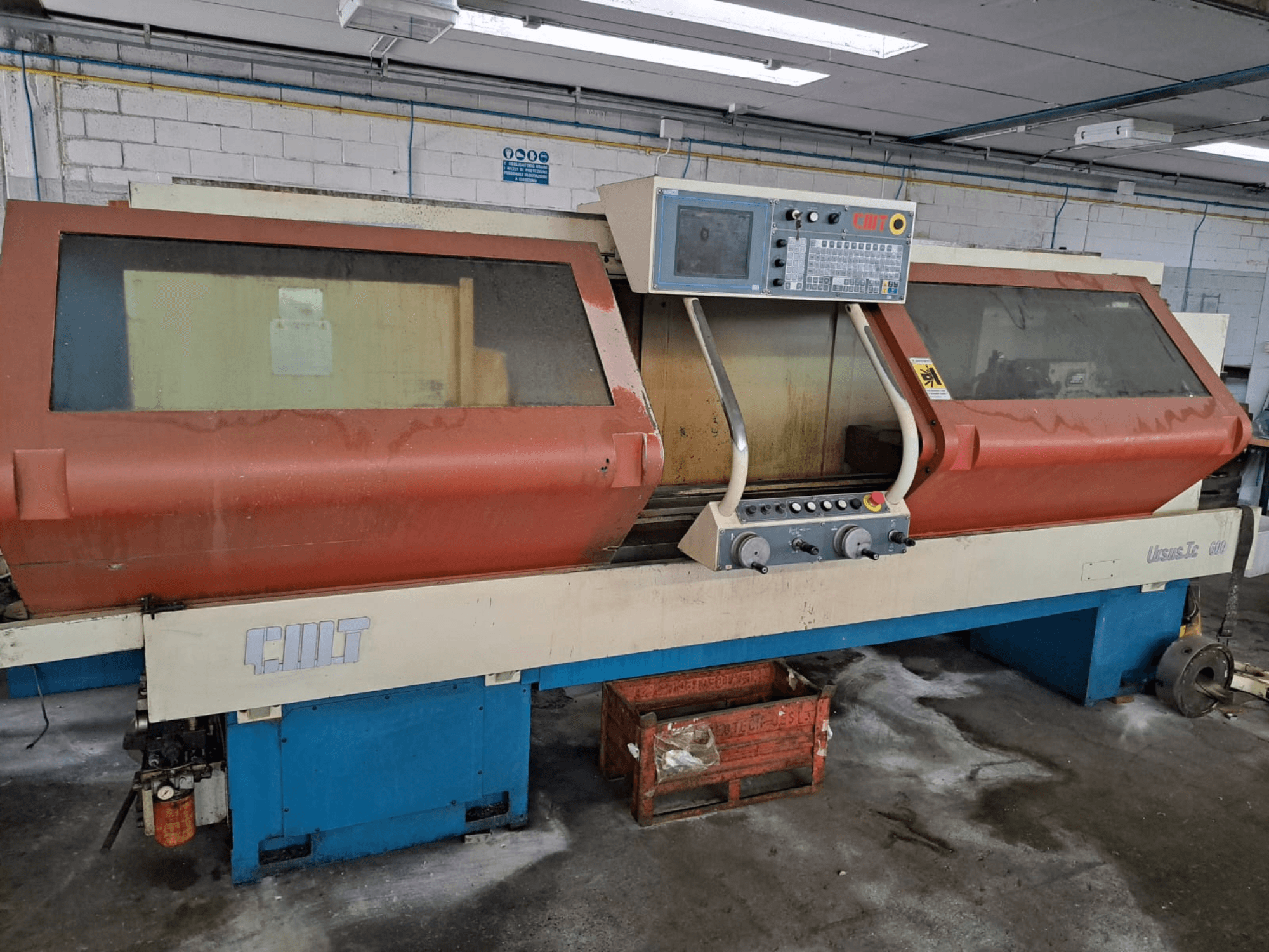 Horizontalios tekinimo staklės URSUS TC, vaizdas iš priekio, su raudonu korpusu, valdymo skydeliu ir matomu įrankių laikikliu.