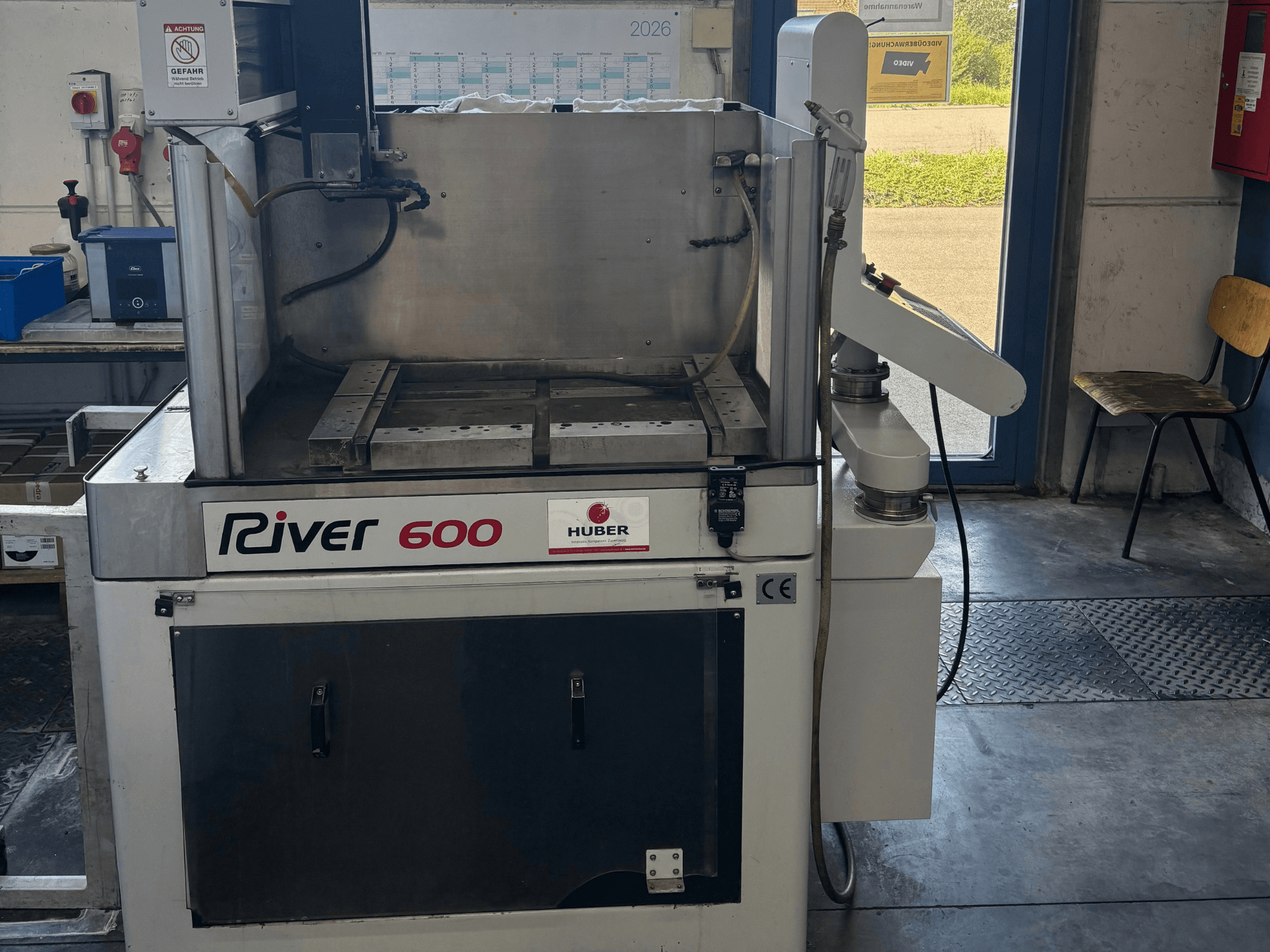 „HUBER River 600“ CNC giluminės elektros erozijos staklės, vaizdas iš priekio, kuriame matoma iš dalies atidaryta darbo kamera ir valdymo pultas.