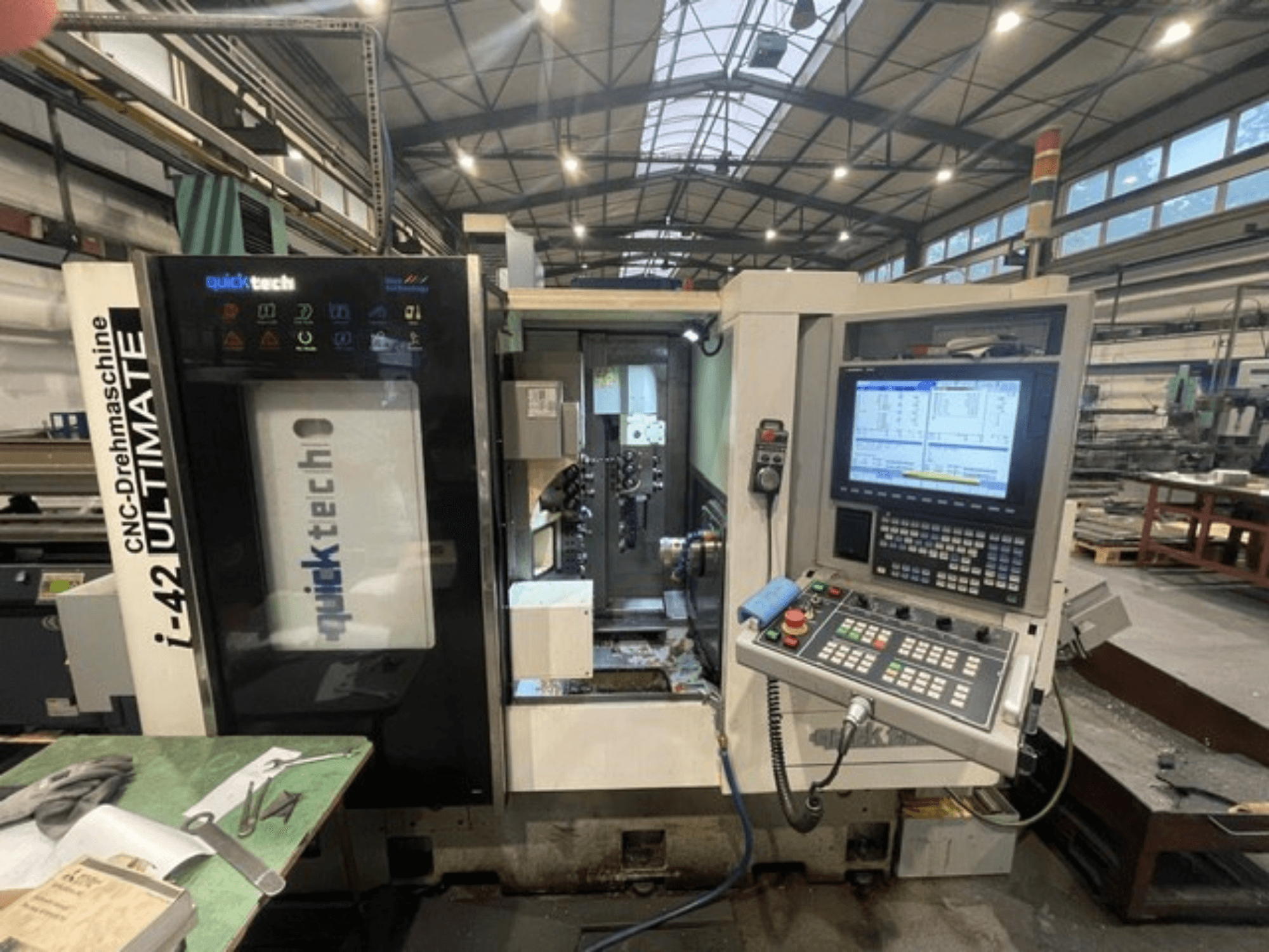 "Quick-Tech I-42U" šveicariško tipo tekinimo staklės, priekinis vaizdas, kuriame matomas valdymo skydelis ir CNC sąsaja dirbtuvėse.