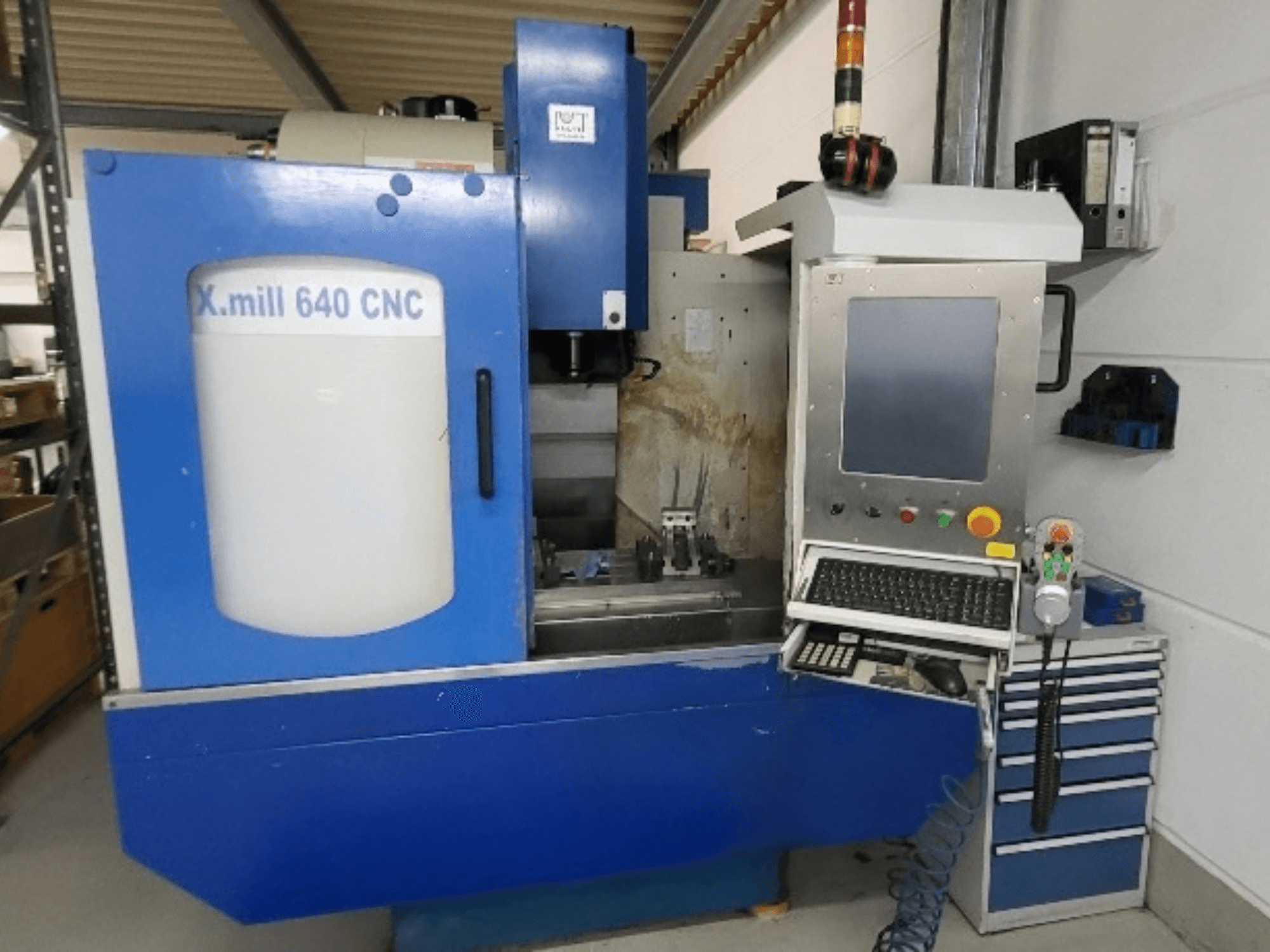 Mėlynas „KNUTH X-mill 640“ CNC vertikalus apdirbimo centras, vaizdas iš priekio, kuriame matomas valdymo pultas ir klaviatūra.