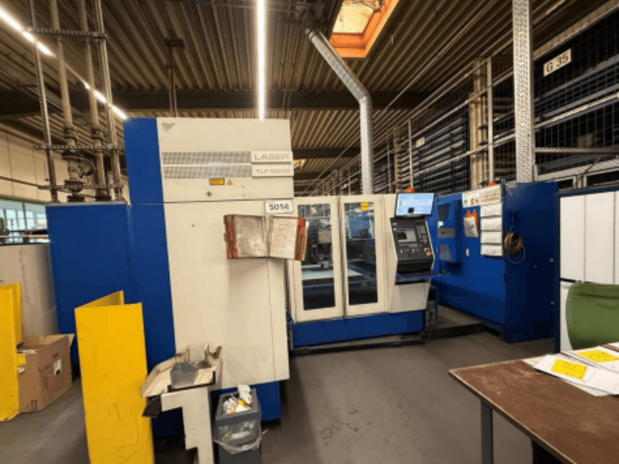 "TRUMPF Trumatic L 3050" CO2 lazerinio pjovimo staklių "Trumatic L 3050" vaizdas iš priekio, kuriame matomas valdymo skydelis ir darbinės funkcijos dirbtuvėse.