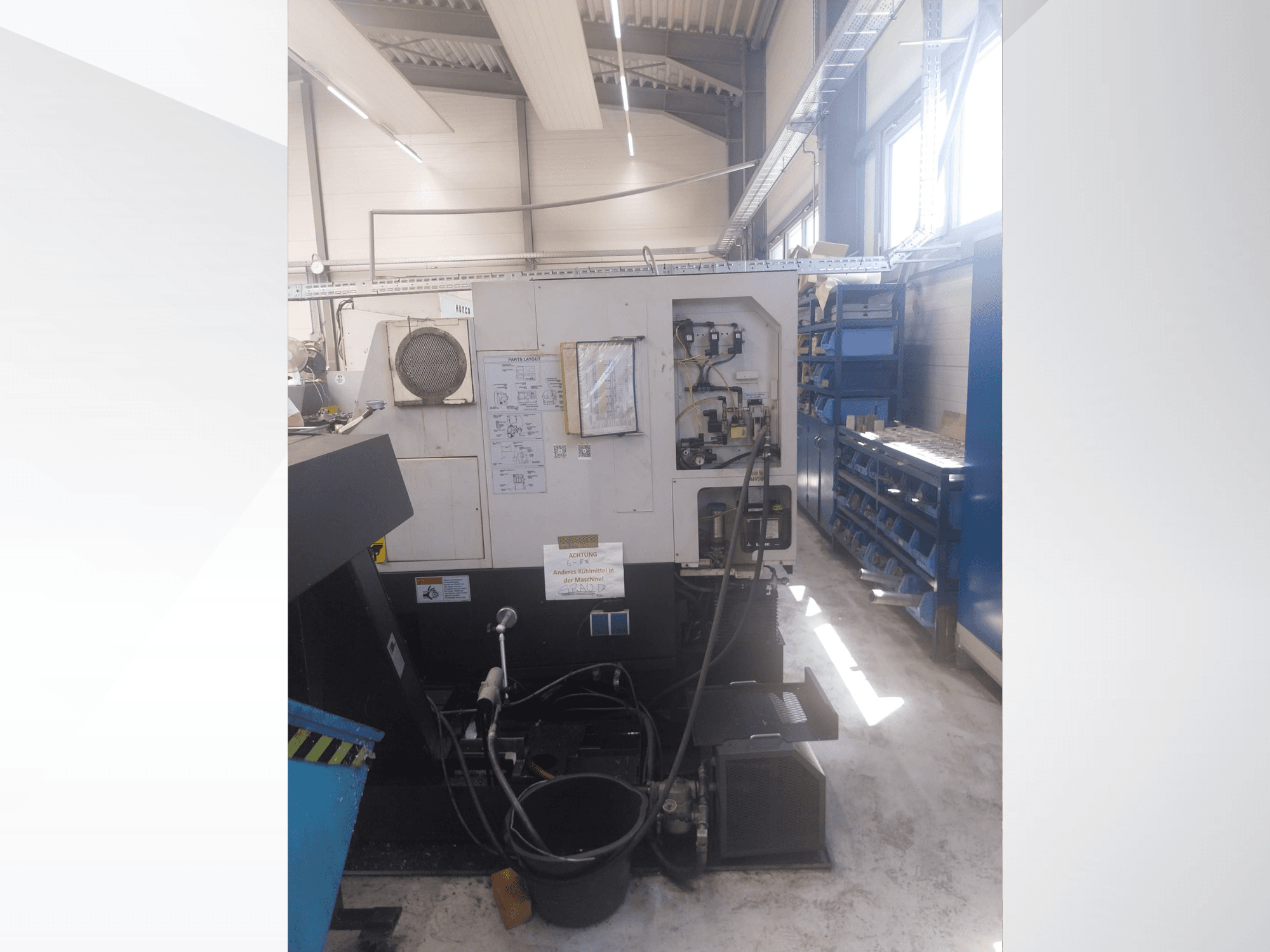 „Mazak QUICK TURN NEXUS 200 MS“ – šoninis vaizdas, kuriame matomas valdymo skydas, žarnos ir įrankių zona dirbtuvėse.