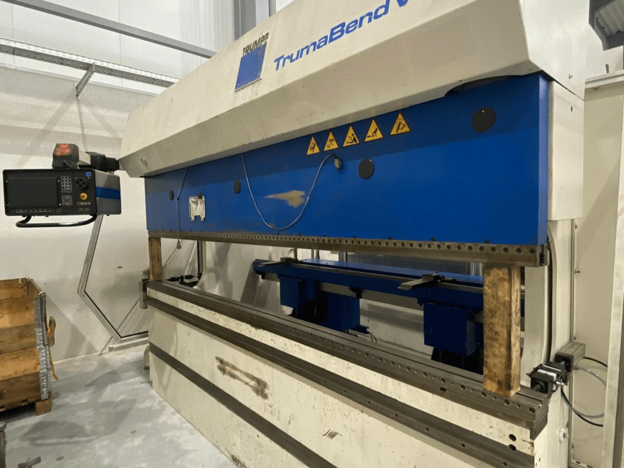 TRUMPF „Trumabend V130“ lenkimo presas, vaizdas iš priekio, matomas valdymo pultas, mėlyni elementai ir saugos įspėjamieji užrašai.