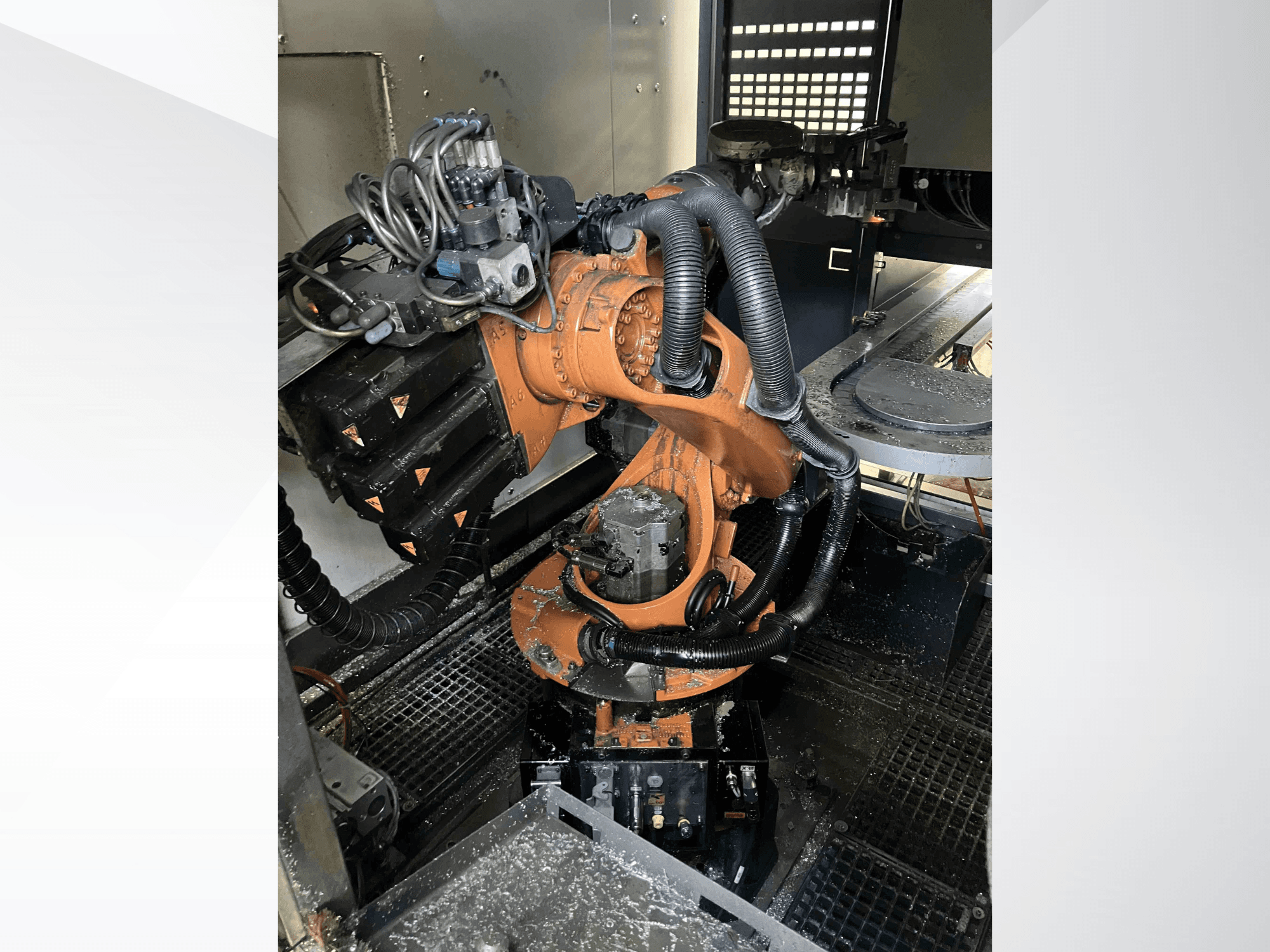 KUKA KR 16 roboto ranka, žiūrint iš viršaus, demonstruojanti mechaninius komponentus ir laidus dirbtuvių aplinkoje.