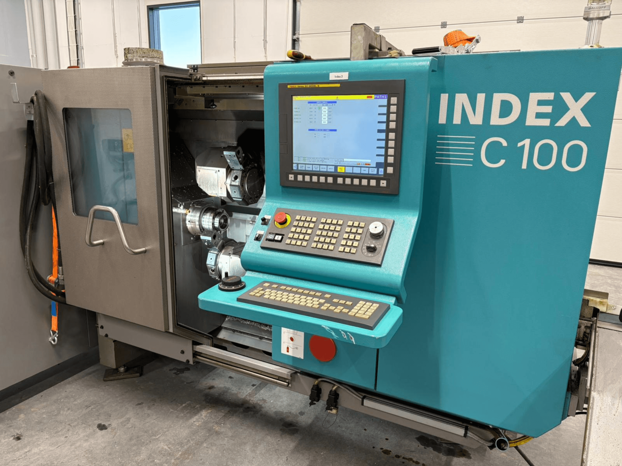 "Index C100" šveicariško tipo tekinimo staklių priekinis vaizdas su valdymo skydeliu ir atviru korpusu, kuriame matomi vidiniai komponentai.