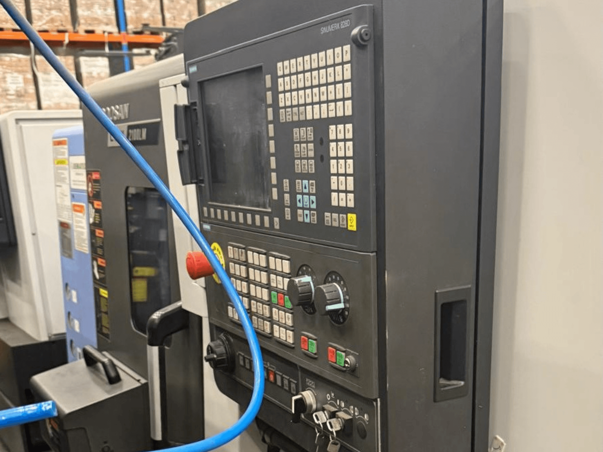 Apdirbimo įrankio valdymo skydelis, vaizdas iš priekio, su mygtukais, rankenėlėmis ir skaitmeniniu ekranu, skirtu tiksliam valdymui.