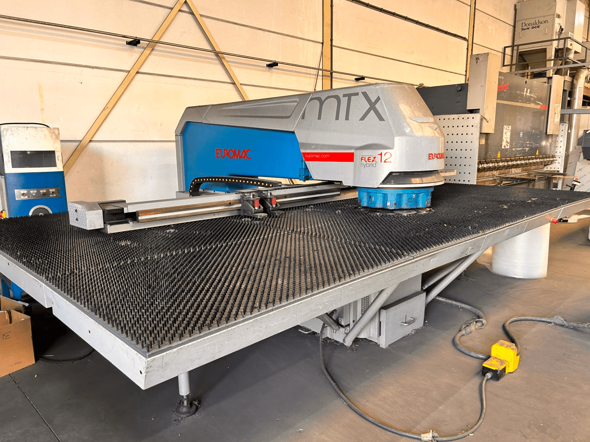 „Euromac MTX FLEX 12“ CNC perforavimo staklės, vaizdas iš priekio, su dideliu perforuotu stalu ir valdymo pultu.