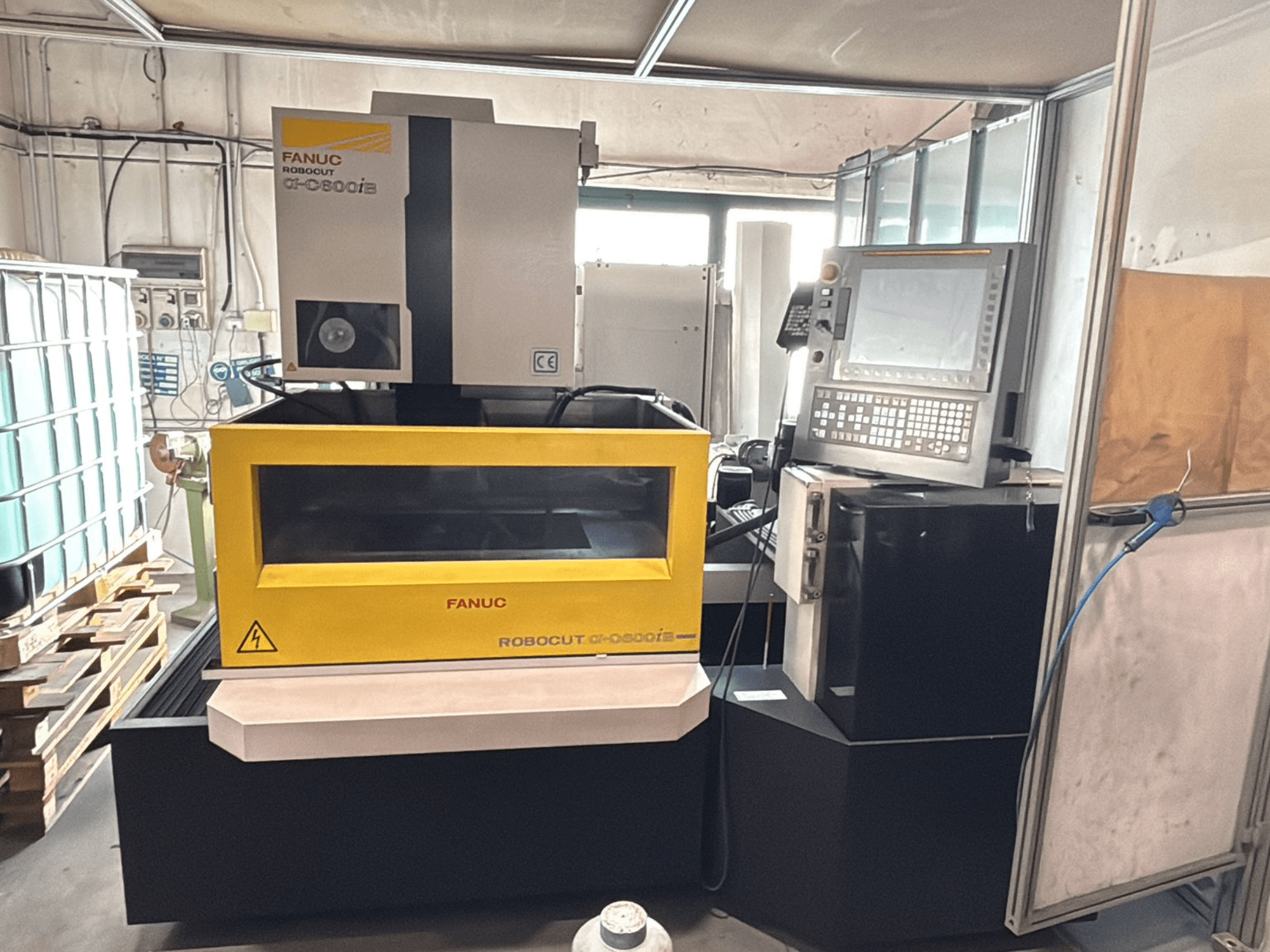 FANUC Robocut α-0iE CNC staklių su geltonu korpusu priekinis vaizdas, kuriame matomas valdymo skydelis ir ekranas.