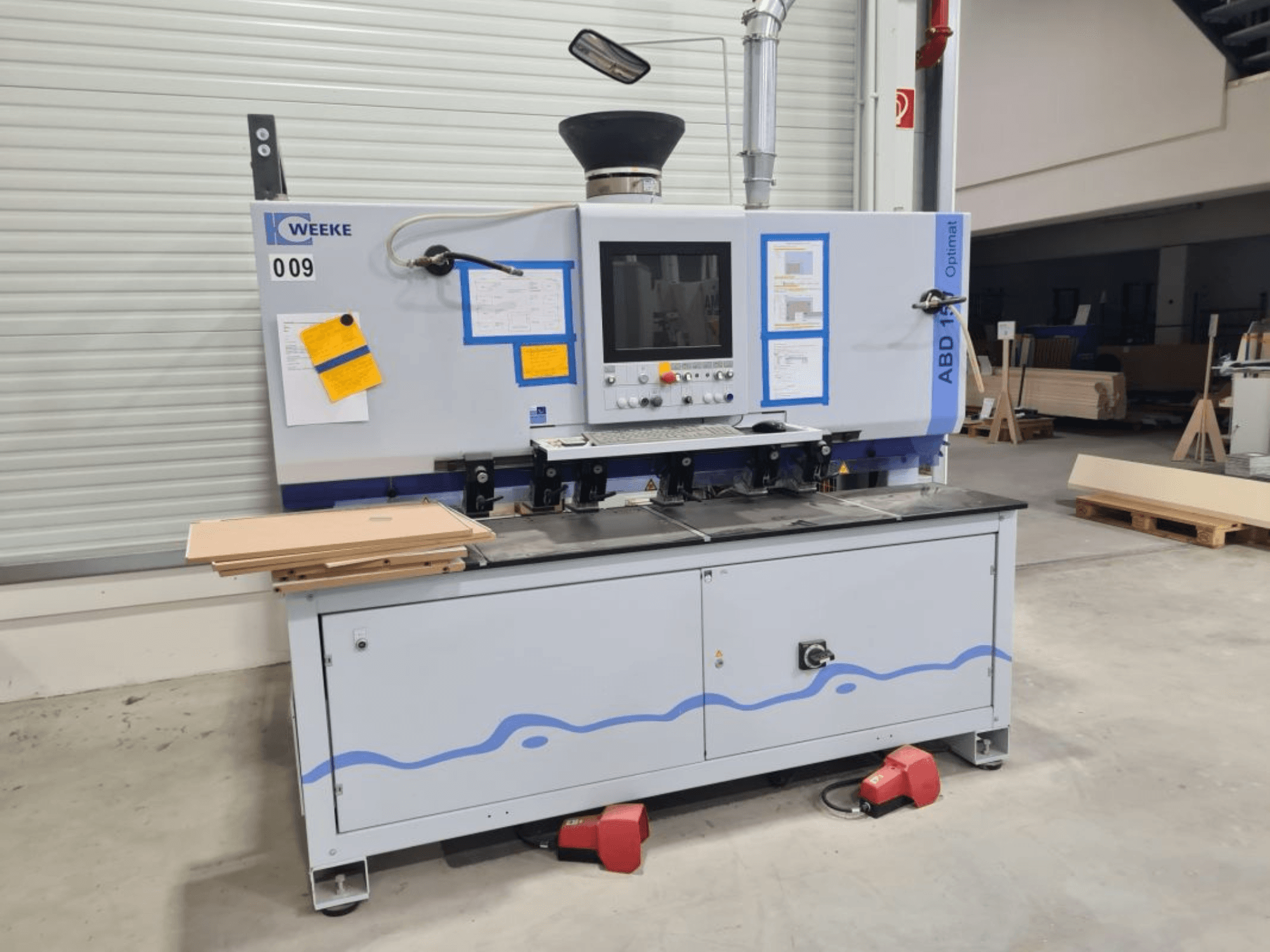 HOMAG WEEKE OPTIMAT ABD150 daugiasvirtės gręžimo staklės, vaizdas iš priekio, matyti valdymo įtaisai ir sudėtos medienos plokštės.