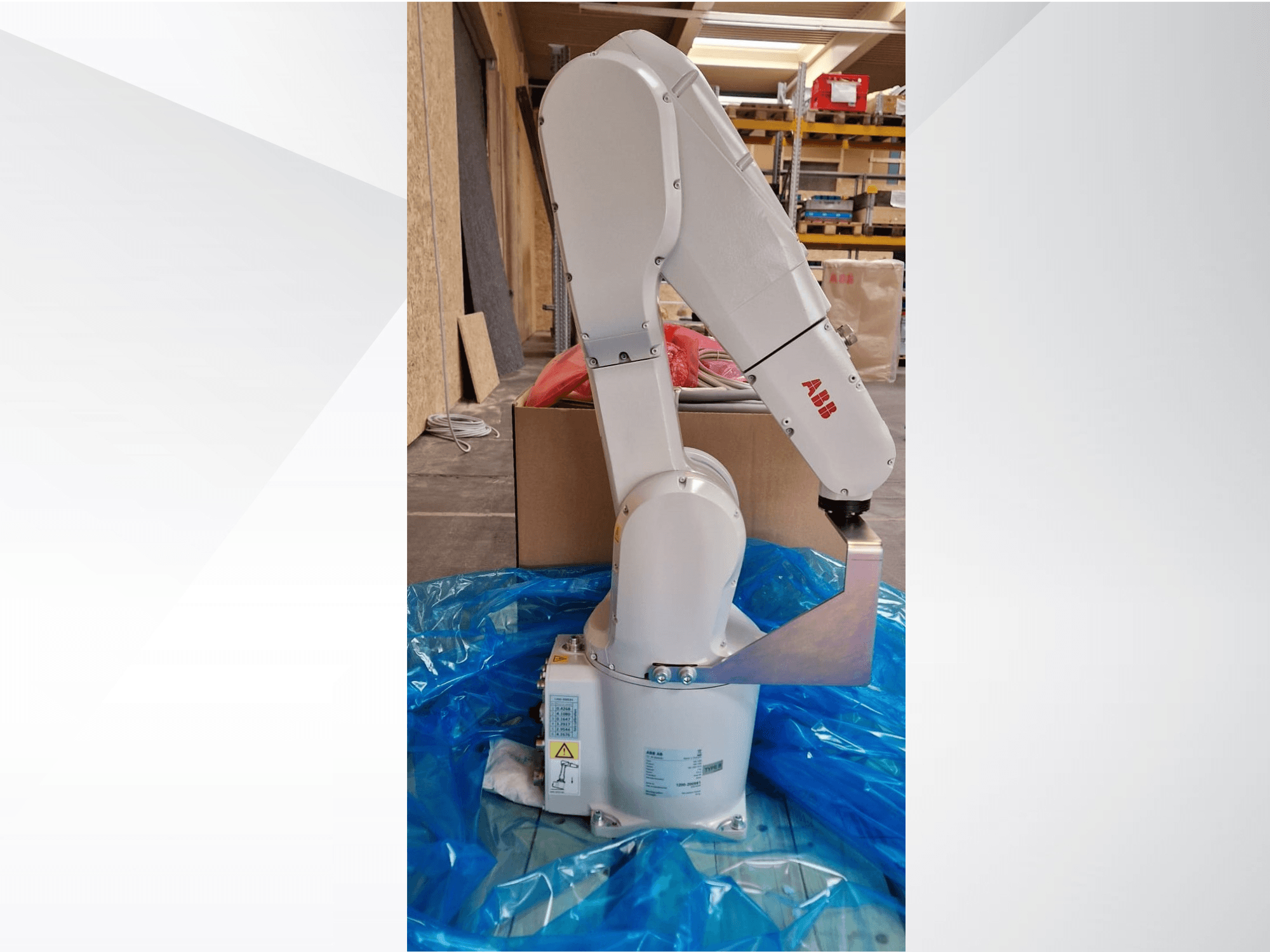 ABB roboto rankos modelis, šoninis vaizdas ant mėlyno brezento, matomi šarnyriniai sąnariai ir metalinis galinis efektorius, matomos techninės etiketės.