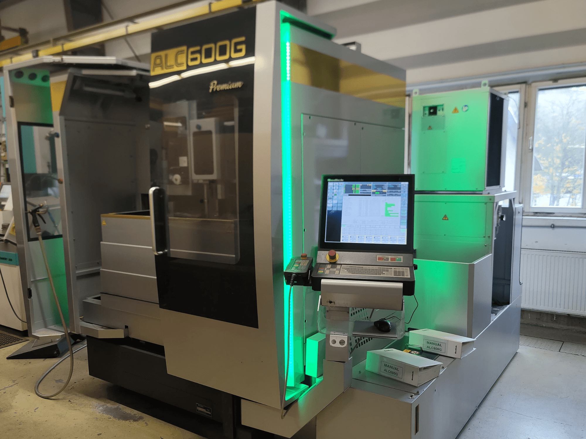 "Sodick ALC600G Premium" vielos EDM staklės, vaizdas iš priekio, matomas valdymo skydelis ir apšviestos išorinės detalės.