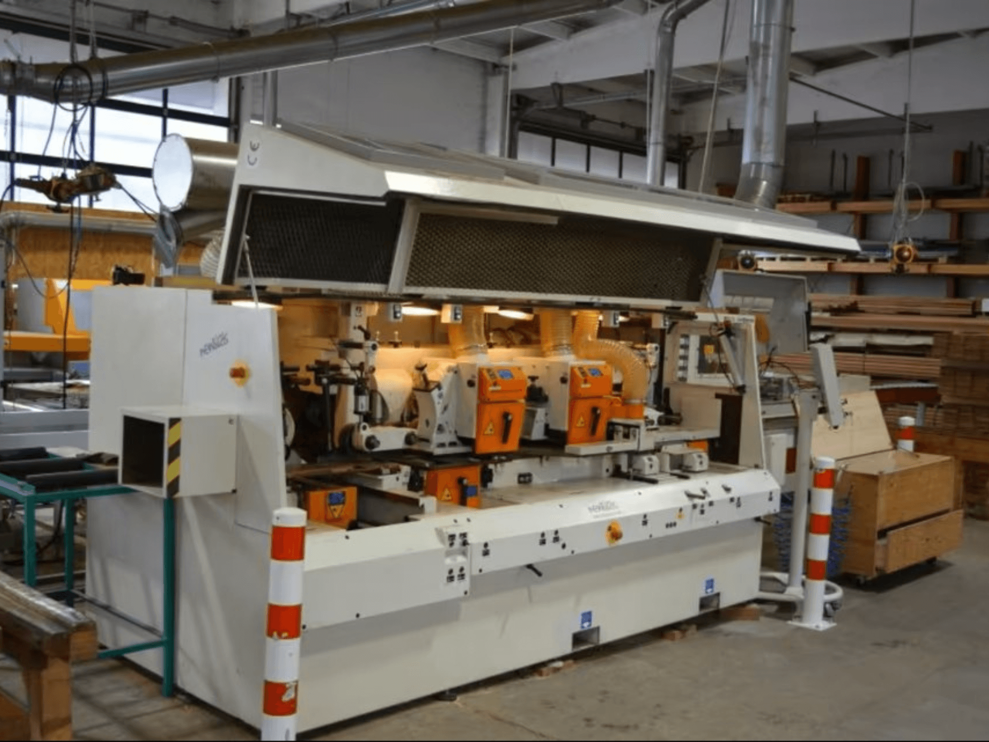 PENIGAS medienos apdirbimo staklės su dviem oranžinėmis pjovimo galvutėmis ir dulkių nusiurbimo sistema dirbtuvėse, vaizdas iš priekio.