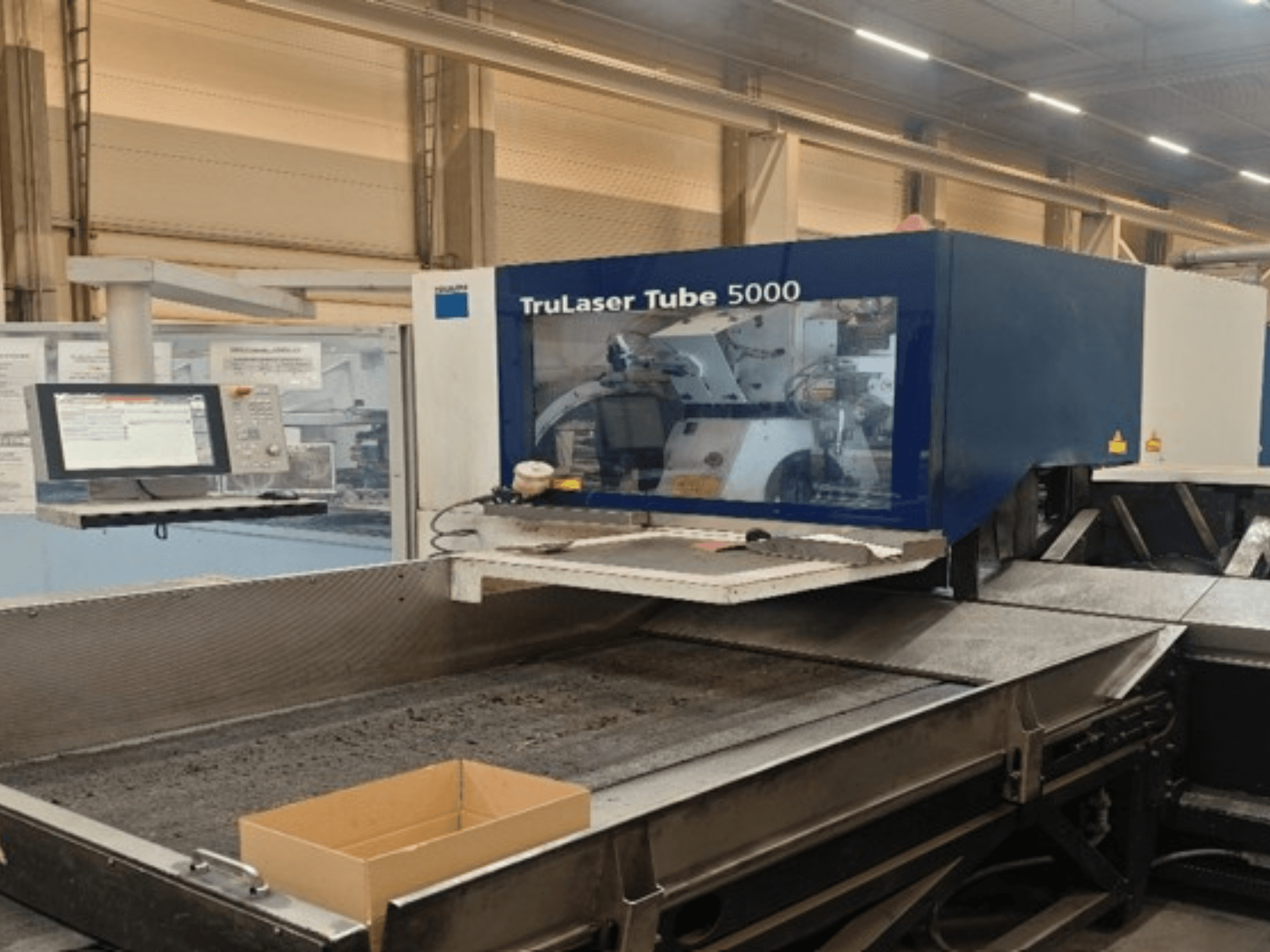 „TRUMPF TruLaser Tube 5000“ vaizdas iš priekio, kuriame matomas valdymo skydas ir pjovimo zona, skirta tiksliam vamzdžių pjovimui.