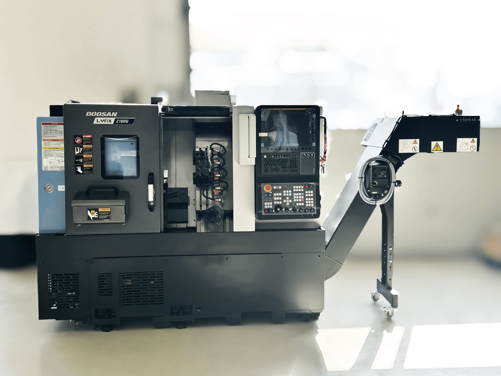DOOSAN LYNX 2100GA šveicariško tipo tekinimo staklės iš šono, matomas valdymo skydelis ir įrankių laikiklis.