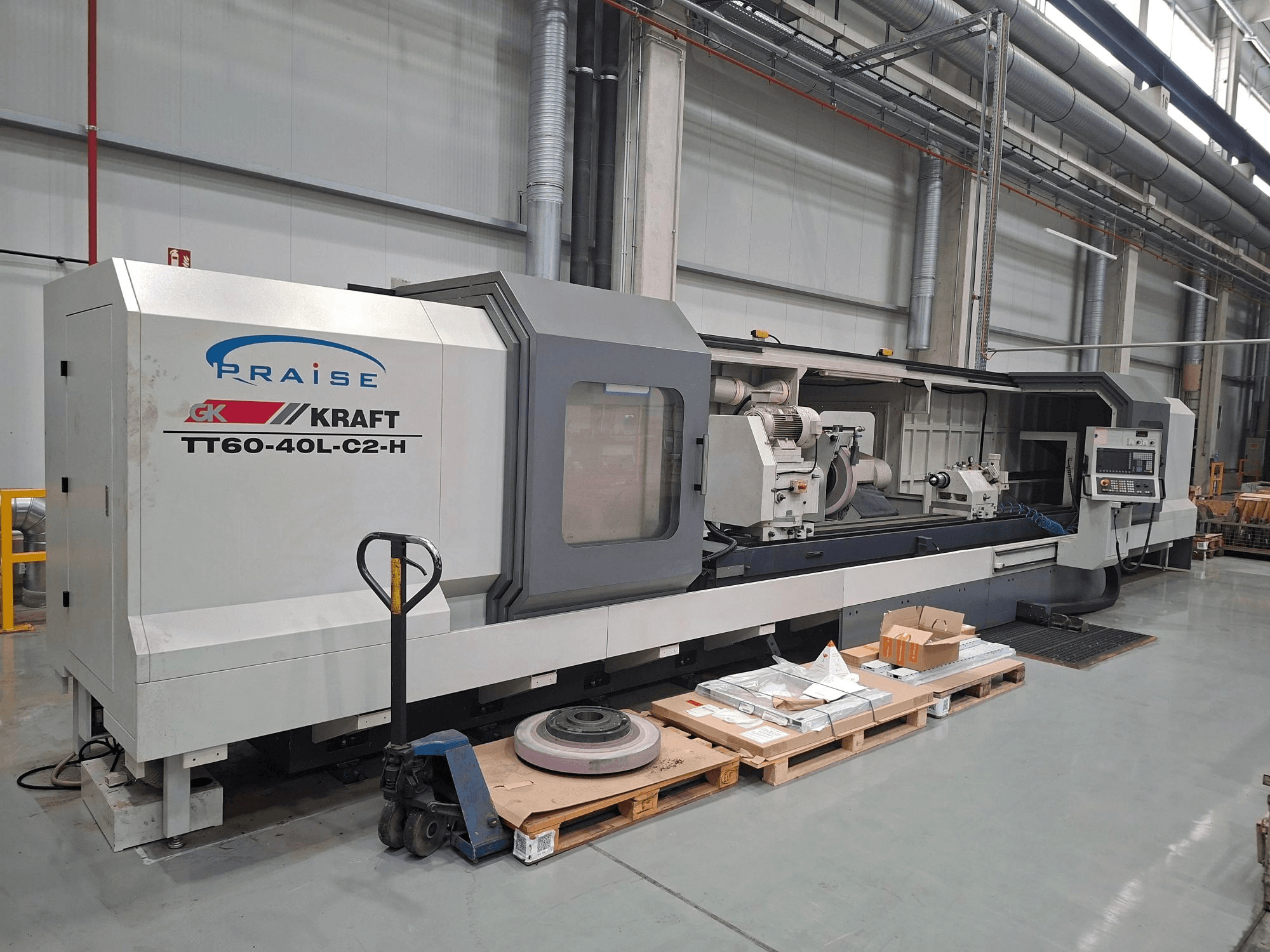 Cilindrinių detalių šlifavimo staklės „KRAFT TT60-40L-C2-H“, vaizdas iš šono, kuriame matomi valdymo elementai ir šlifavimo diskas dirbtuvėse.