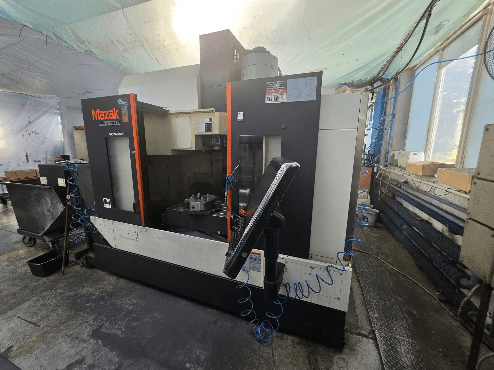 „Mazak VCN-530C“ vertikalaus apdirbimo centro vaizdas iš priekio, kuriame matomas valdymo pultas, darbo zona ir įrankių laikiklis.
